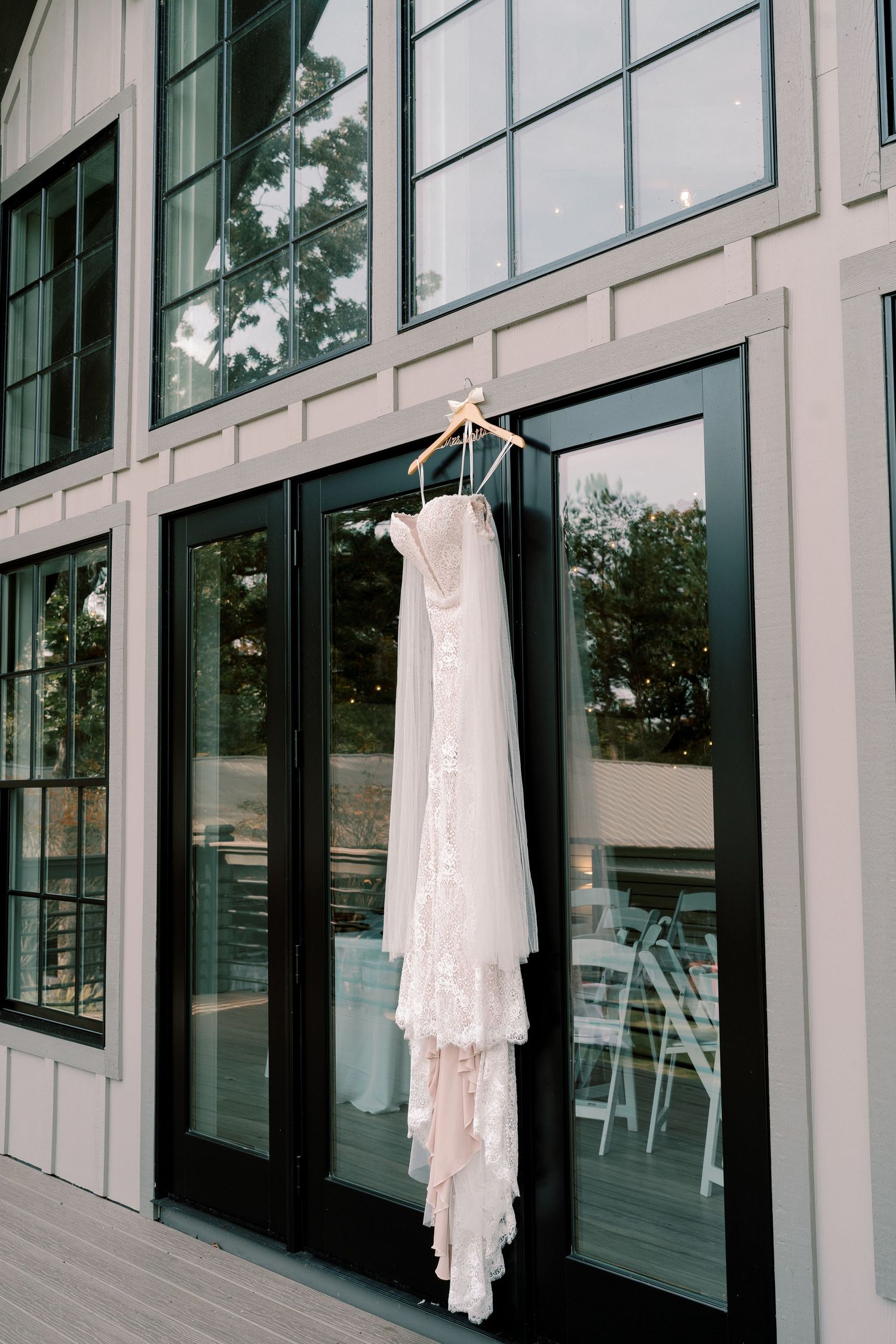 Elegant white wedding dresses displayed against modern glass windows in venue.