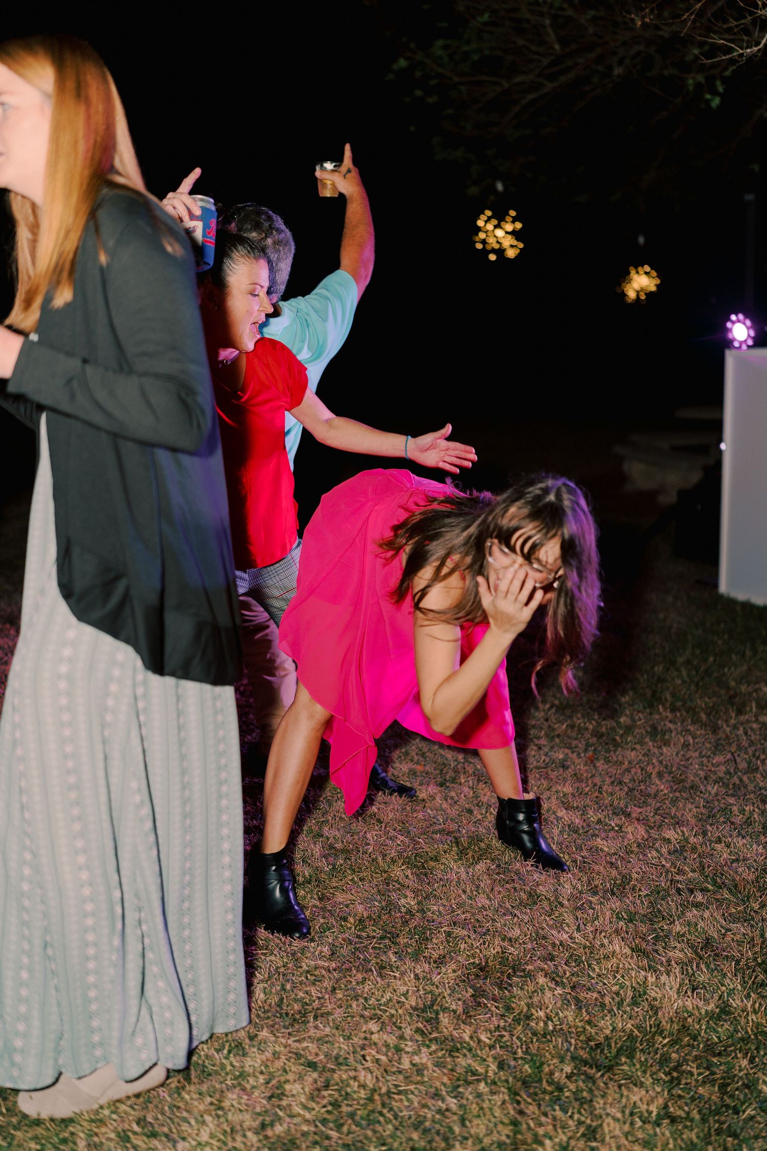 Wedding party dancing energetically at night with colorful dresses and lighting.