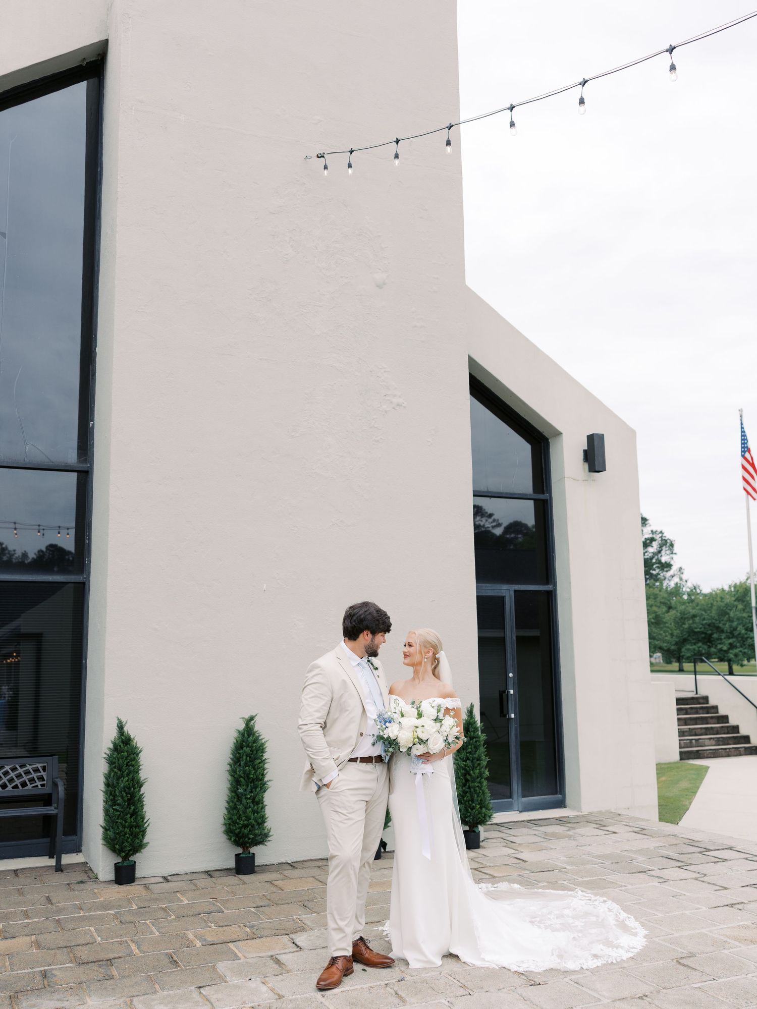 Modern white wedding venue exterior with string lights and minimalist architecture.