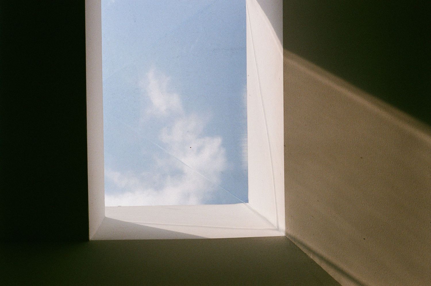 Minimalist architectural detail showing window frames against a bright blue sky.