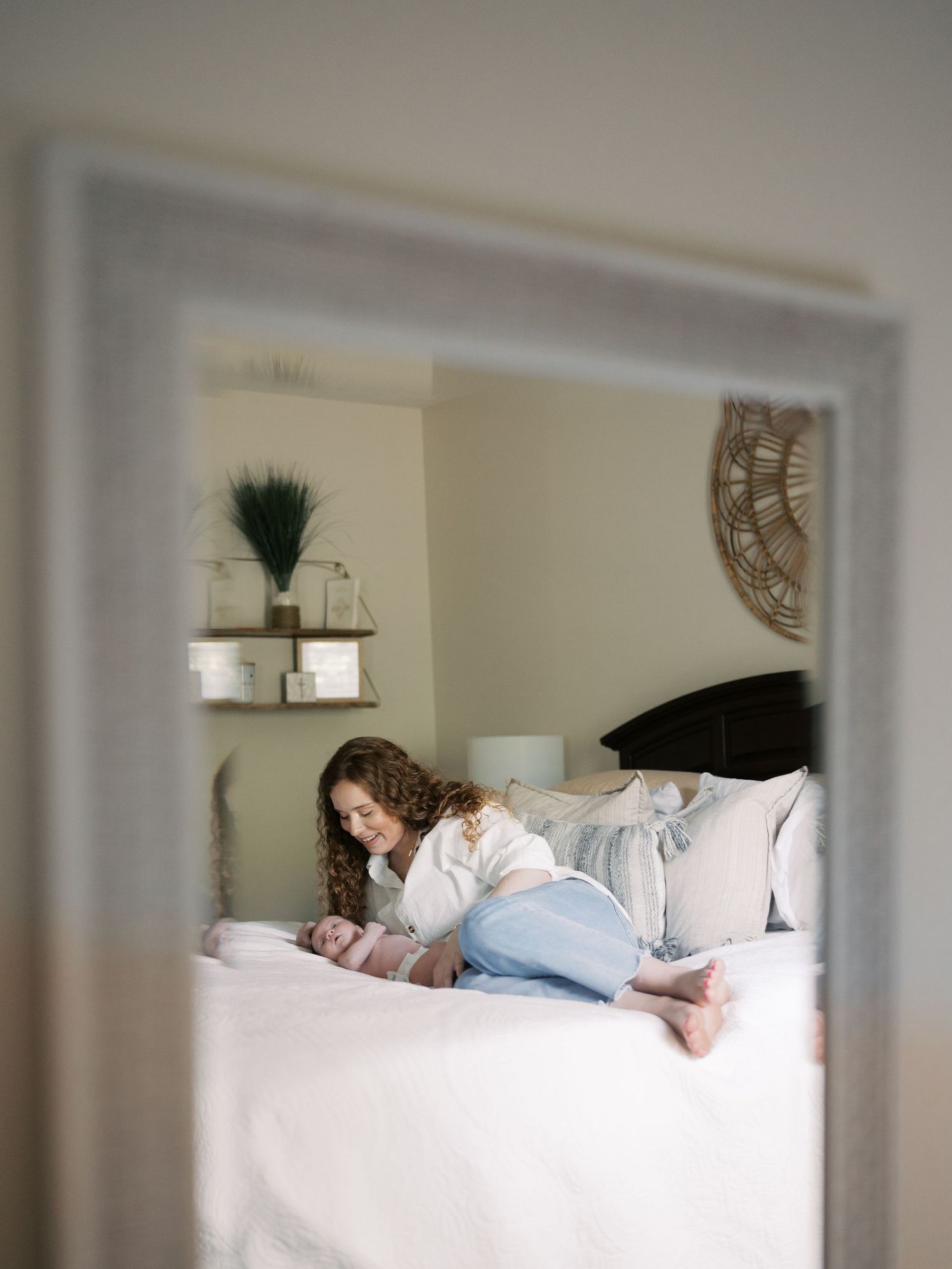 Bedroom scene with family resting together on white bedding and neutral decor.