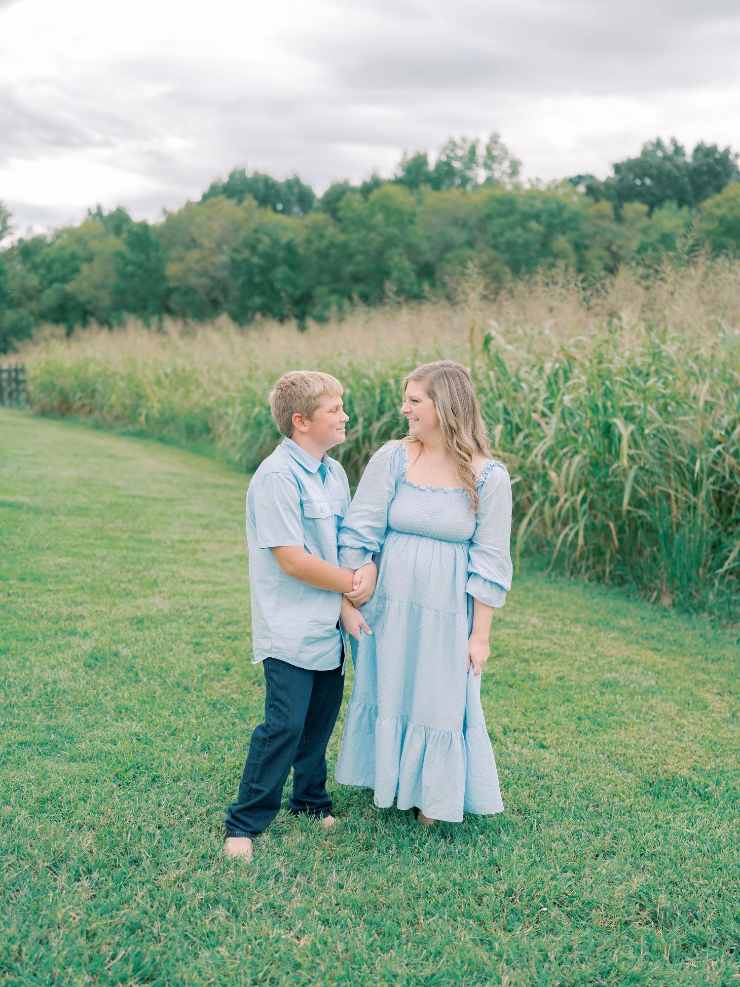 Family members in coordinating blue and white outfits pose together in a grassy field.
