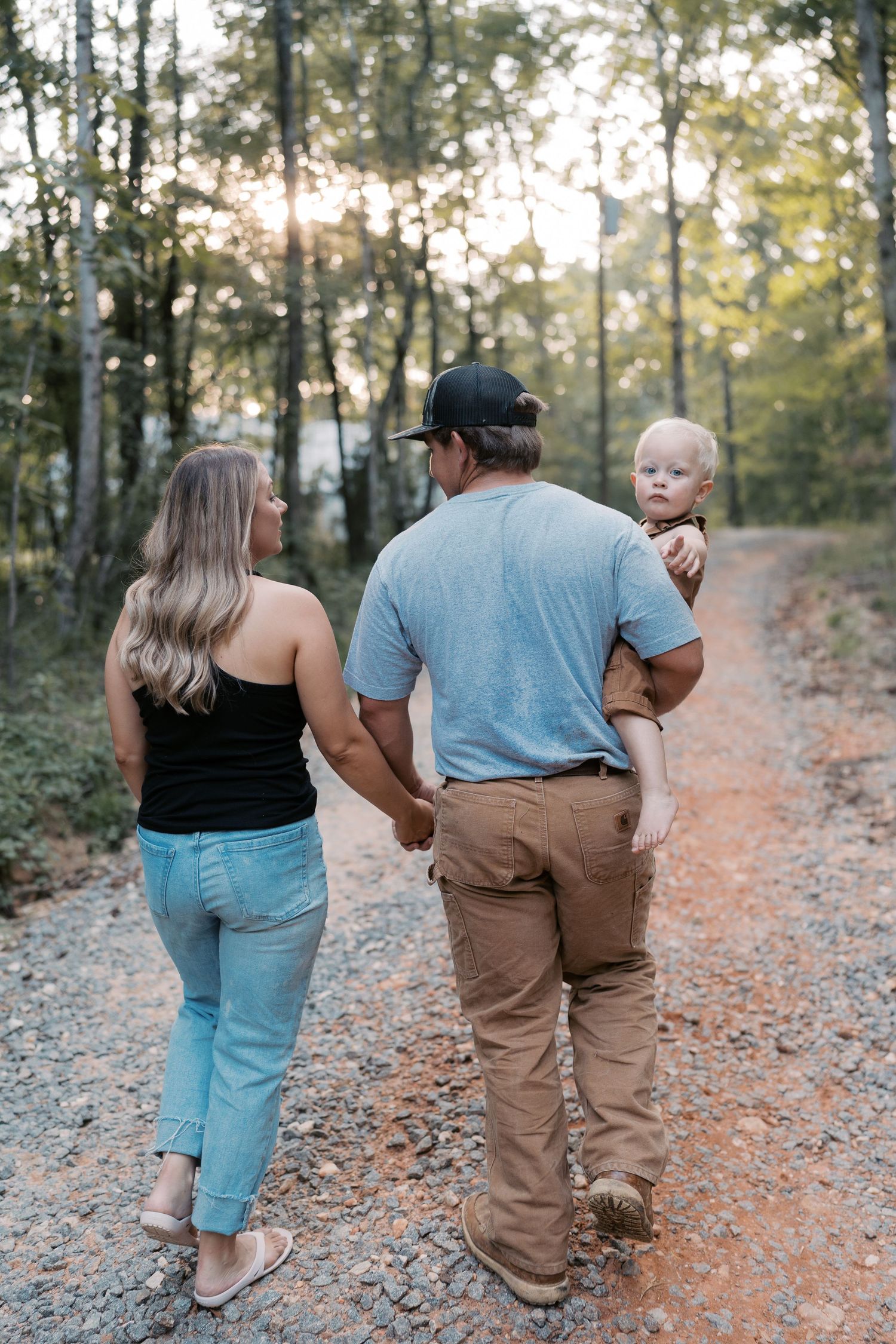 A family walks together down a scenic forest path during golden hour.