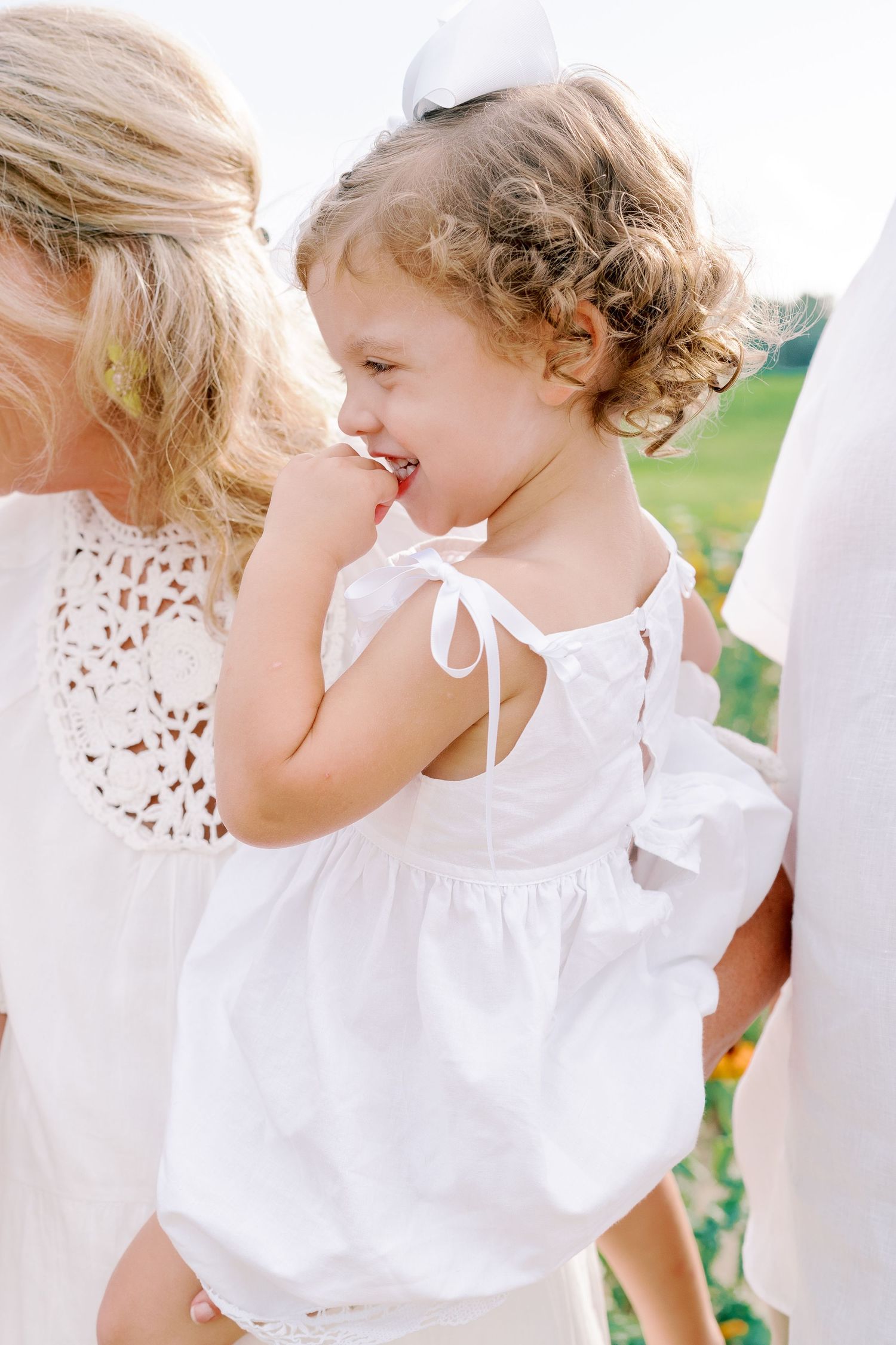 Children in white dresses play together in a flower garden.