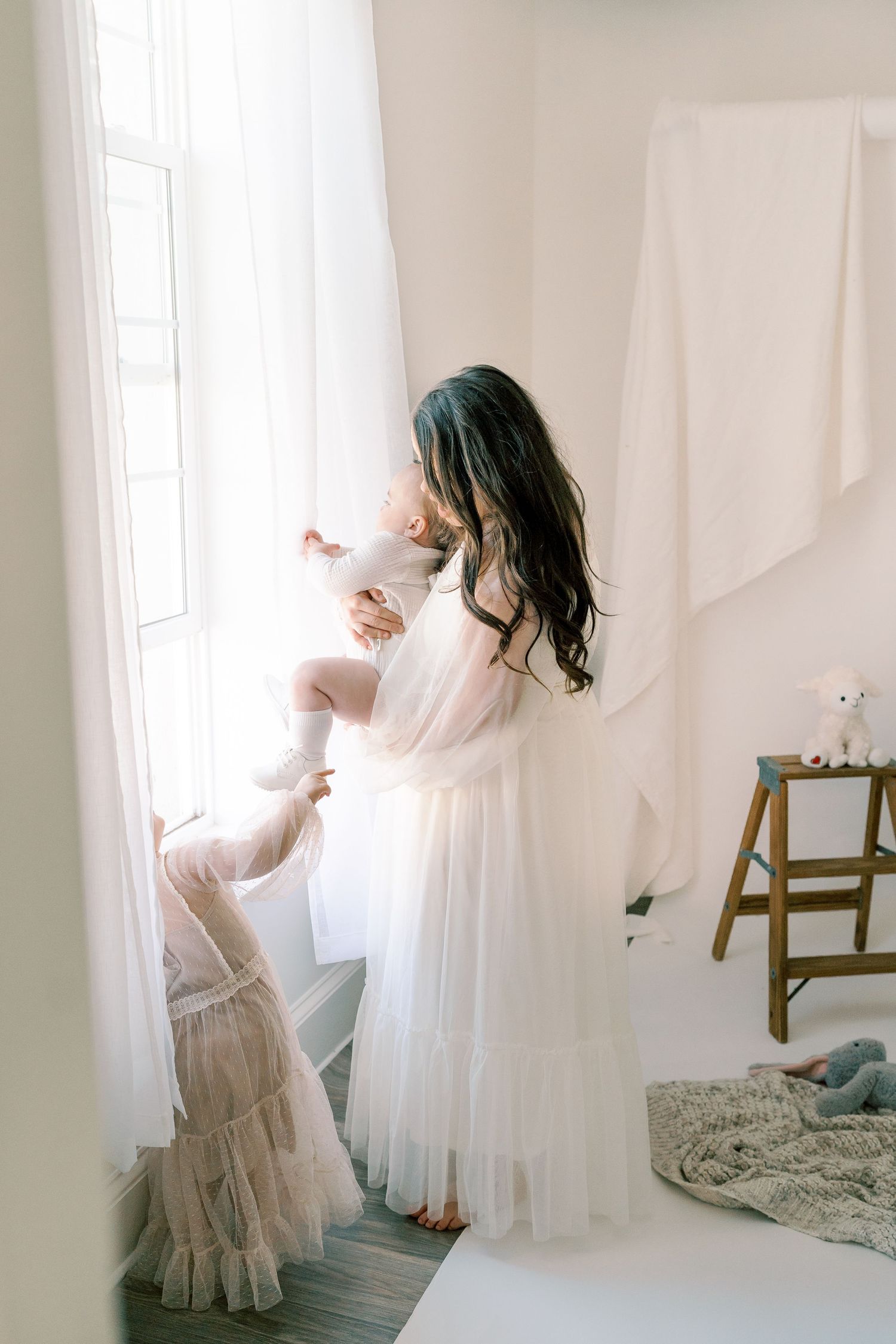 Ethereal scene of flowing white curtains and tulle dress in sunlit room.