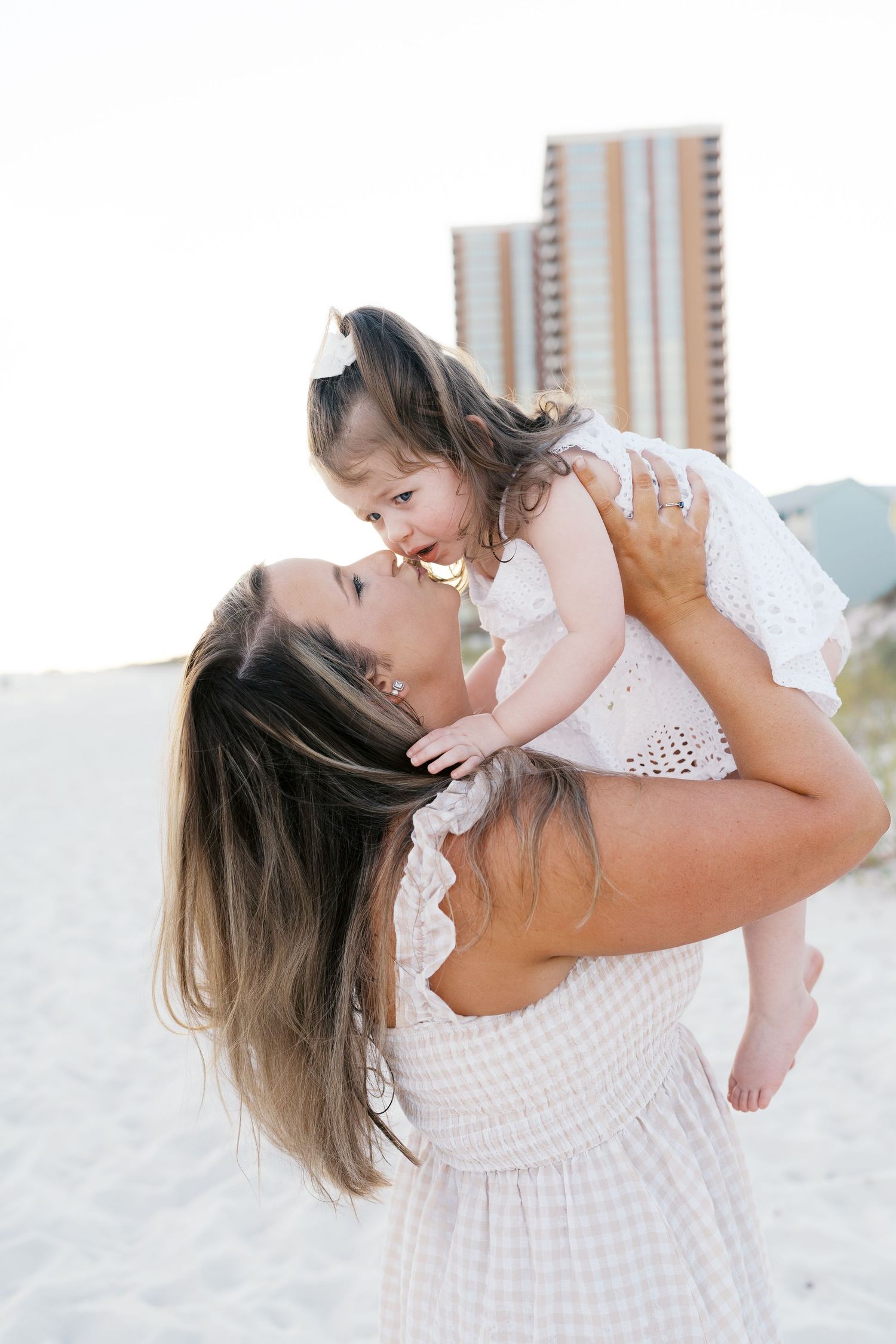 A tender moment between parent and child playing together on a sunny beach.