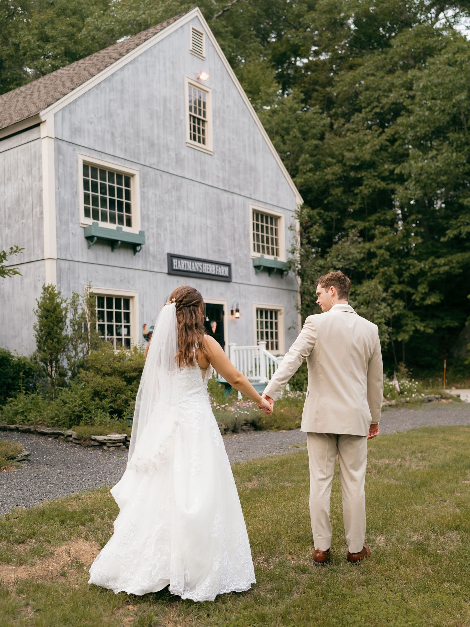 Bride and groom walk hand in hand near a white colonial style building.