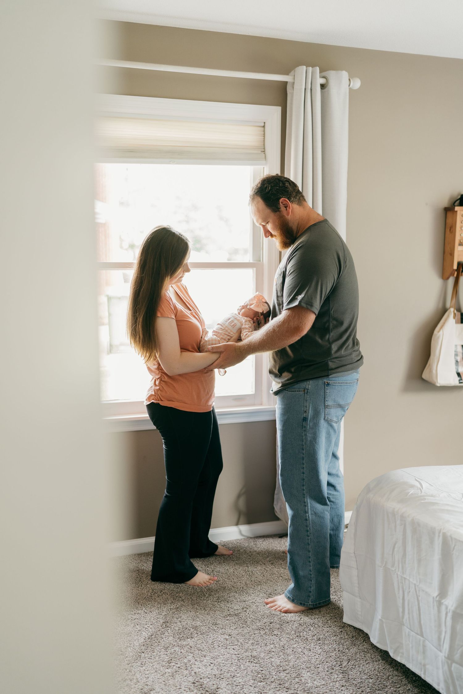 Parents tenderly caring for their newborn in sunlit nursery room.