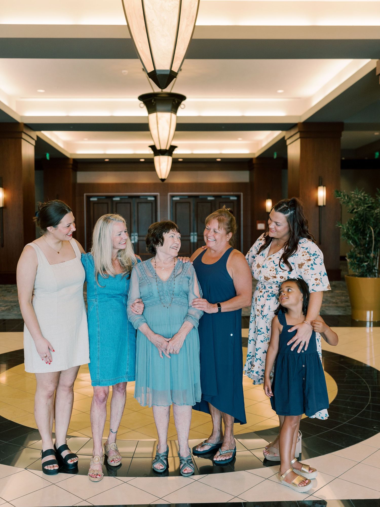 Group photo of people wearing coordinating blue outfits in hotel lobby.