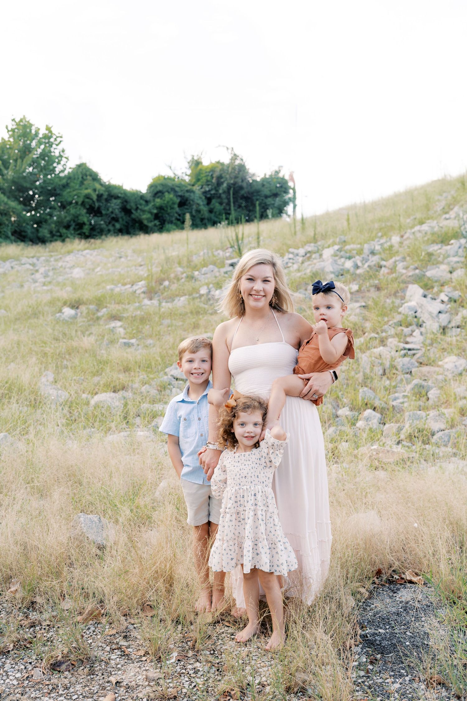 A group poses together in a rustic field with rocks and tall grass.