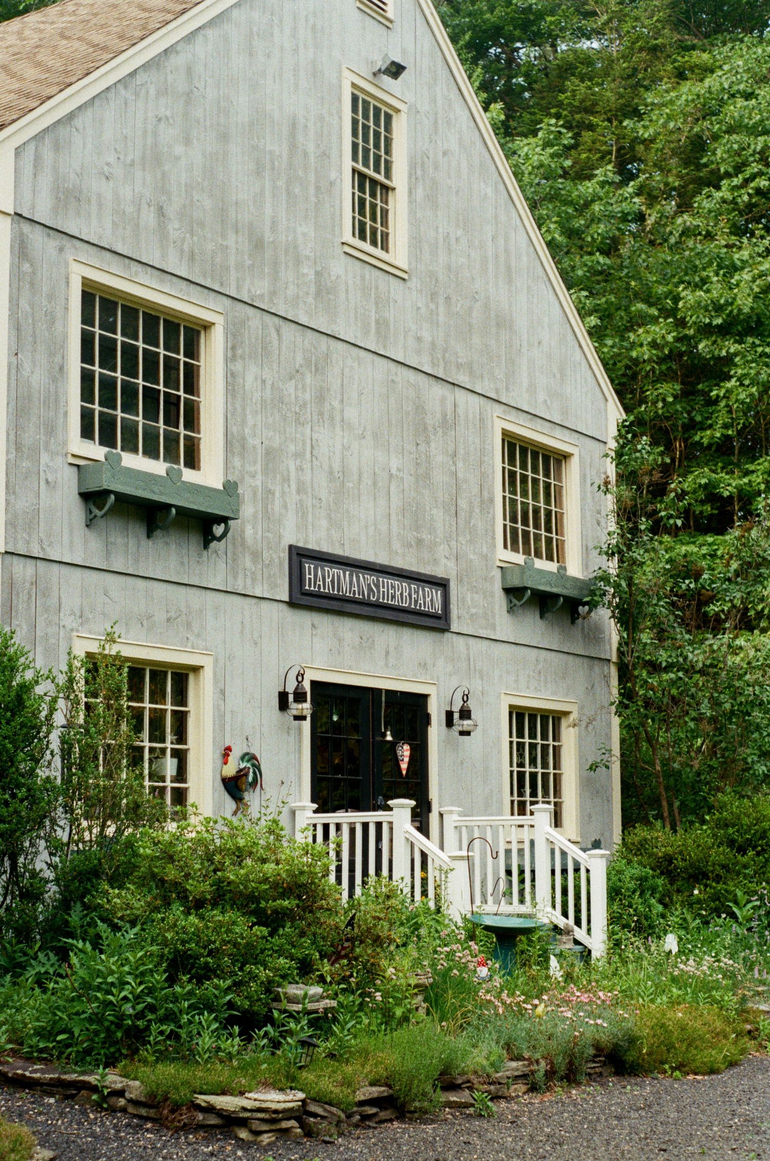 A rustic gray building with white trim and windows labeled as Hartman's Herb Farm.