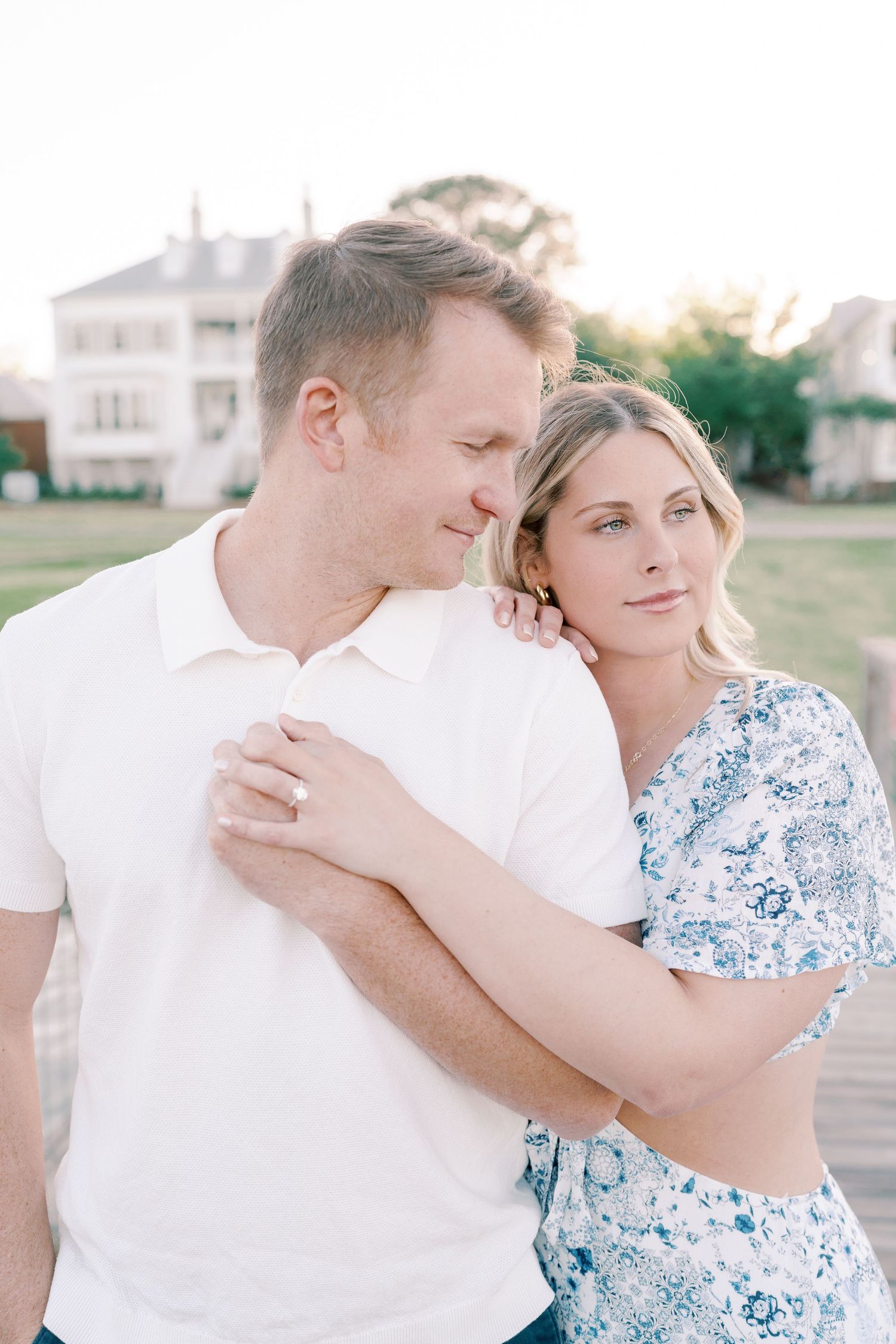 Couple in white and floral dress share intimate moments during sunset photoshoot.