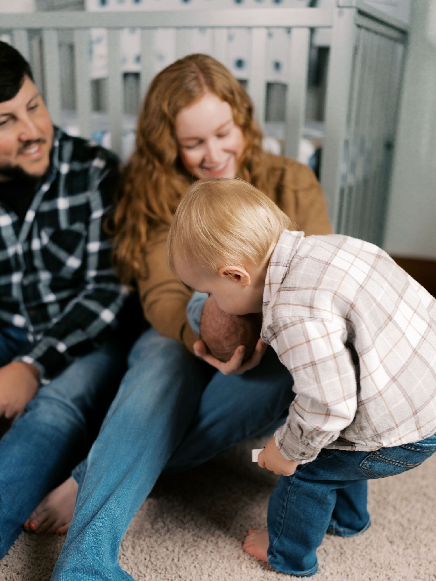 A playful scene of family members sitting on carpet together in a bright room.