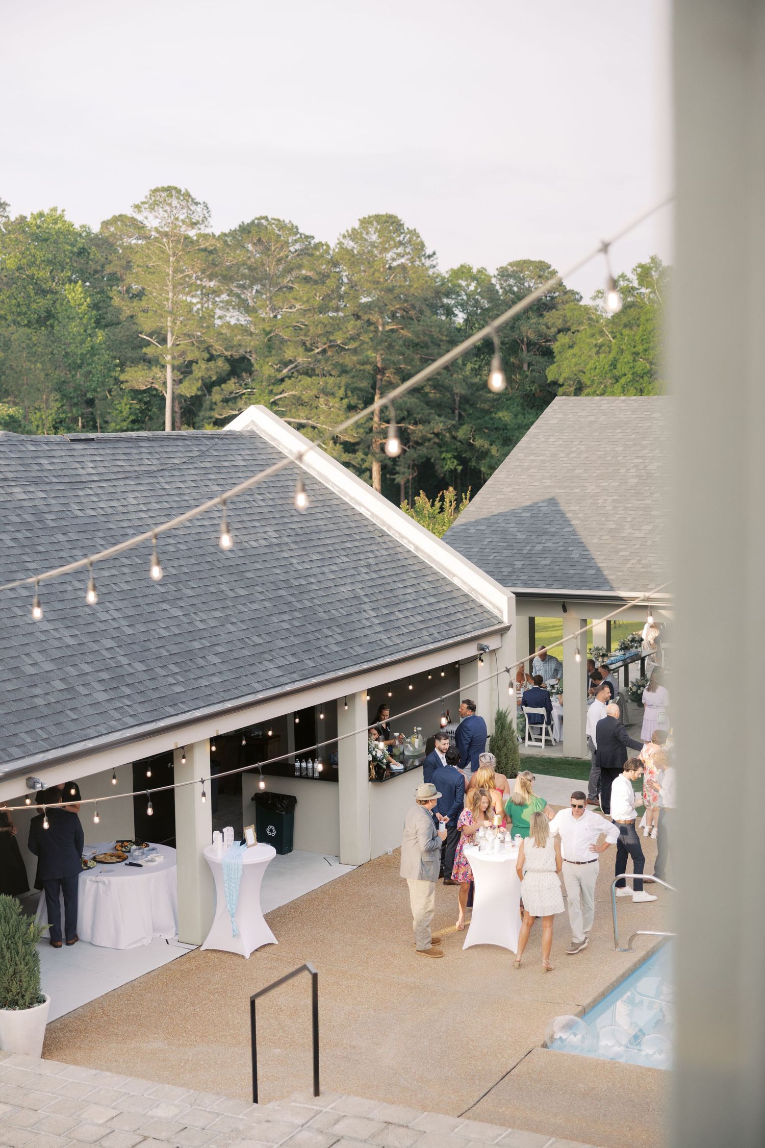 Outdoor wedding reception venue with string lights and guests mingling on the patio.