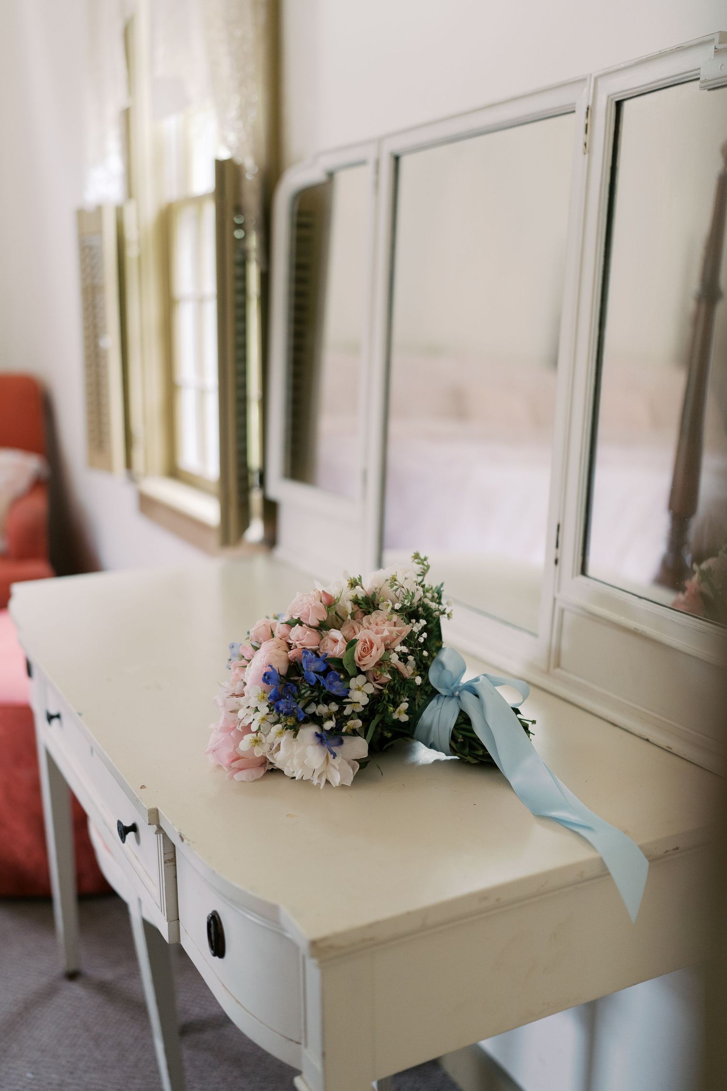 Vintage-style cream colored vanity decorated with soft pastel floral arrangements.