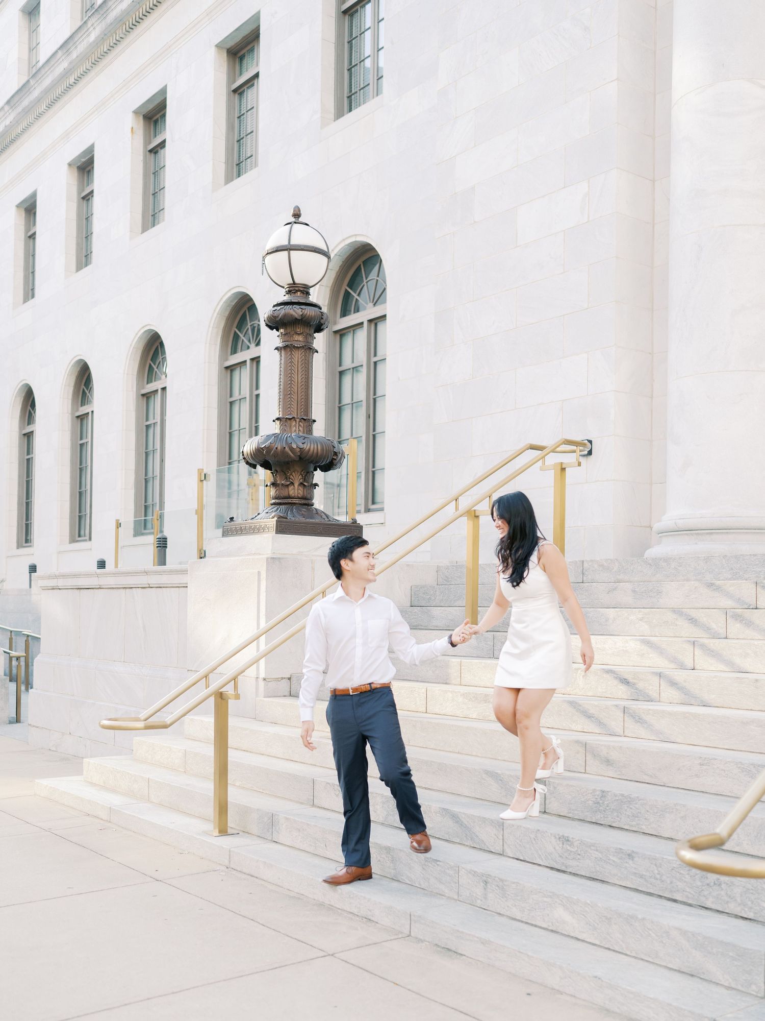 Dancing couple captured in elegant poses on white stone steps with brass railings.
