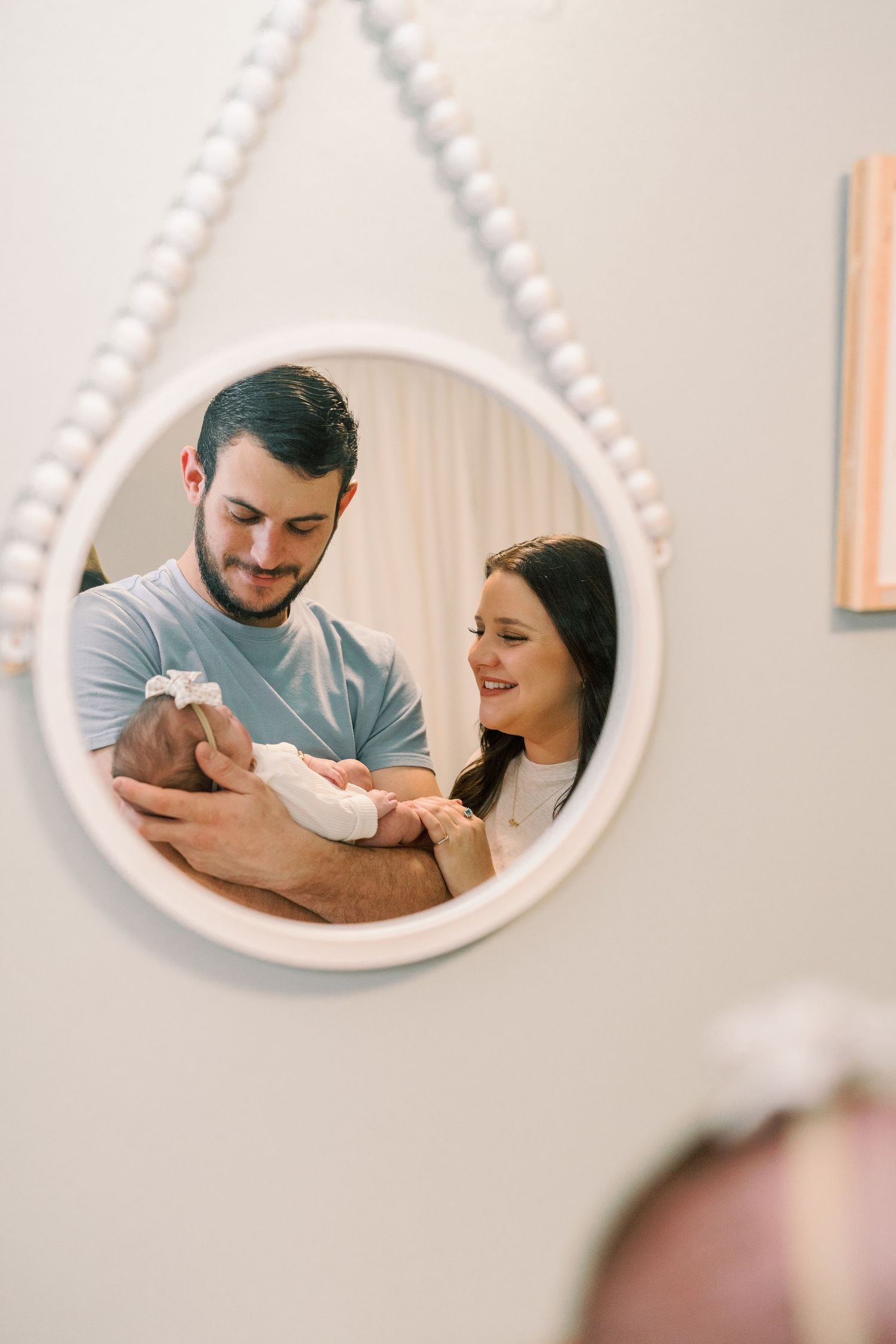 Reflection in oval mirror shows tender family moment.