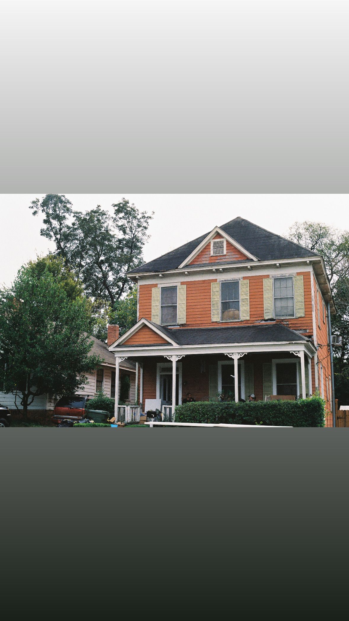 Beautiful orange Victorian style house with white trim and wraparound porch.