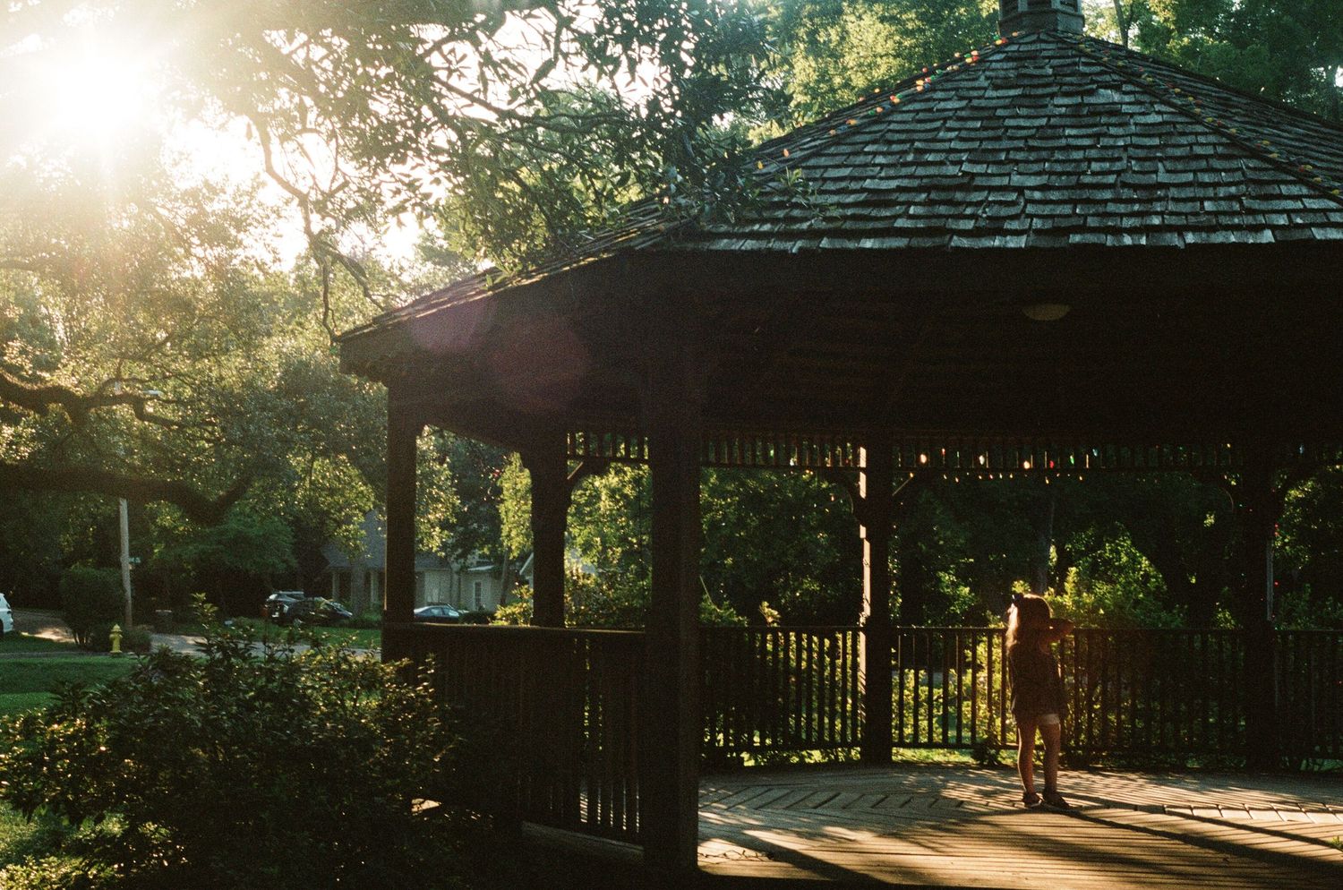 Sunlit outdoor pavilion with wooden beams and string lights at golden hour.