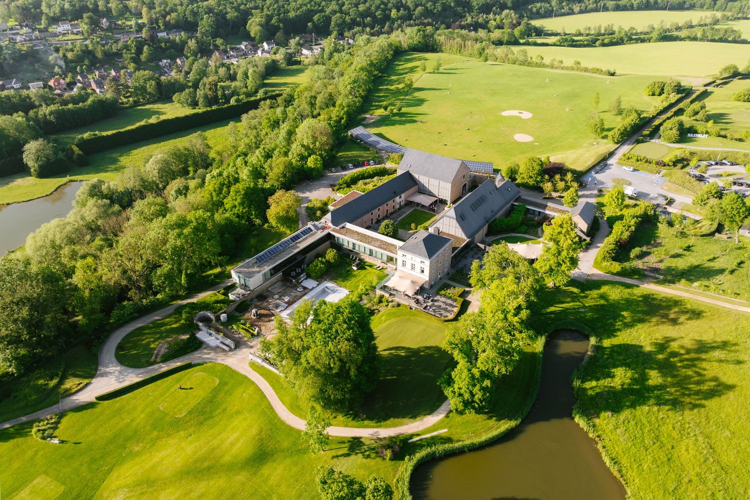 Aerial view of elegant countryside hotel surrounded by lush green golf course and scenic landscape.