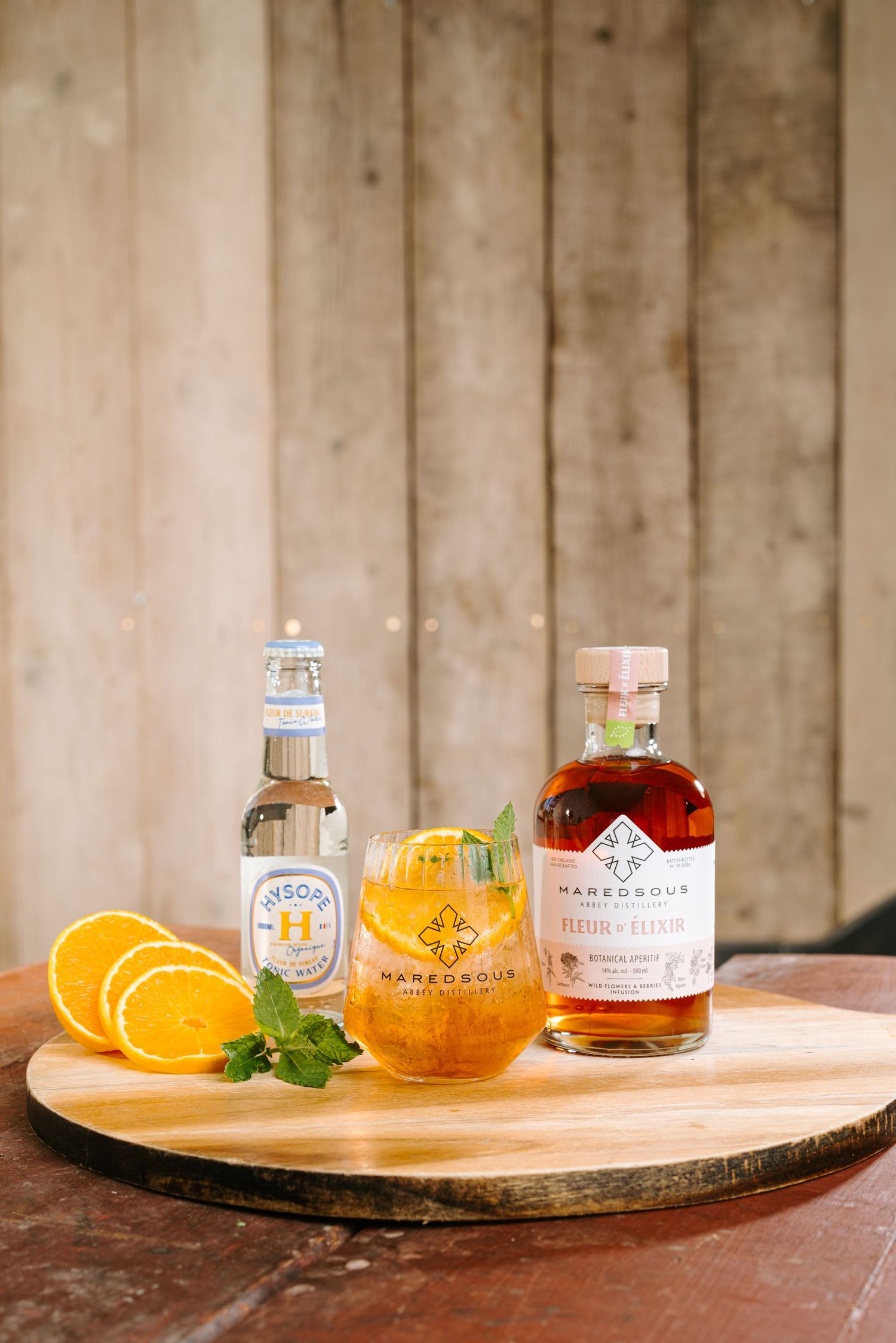 Maredsous abbey distillery liqueur cocktail served with orange slices and mint on a rustic wooden board.