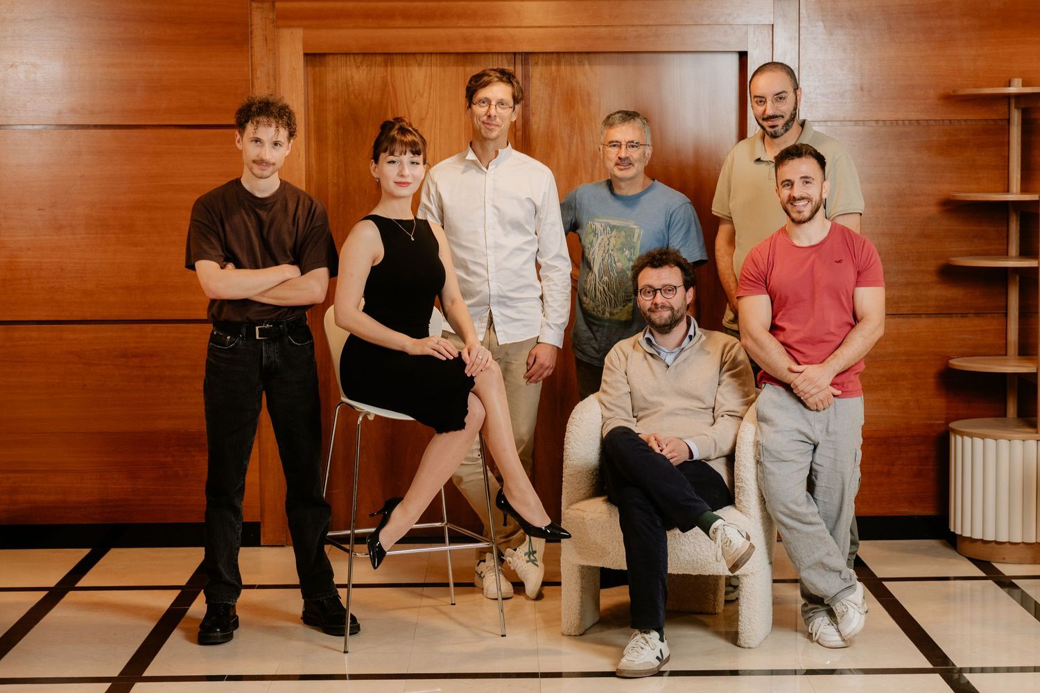 Group of seven professionals smiling together in a modern wood-paneled interior space.