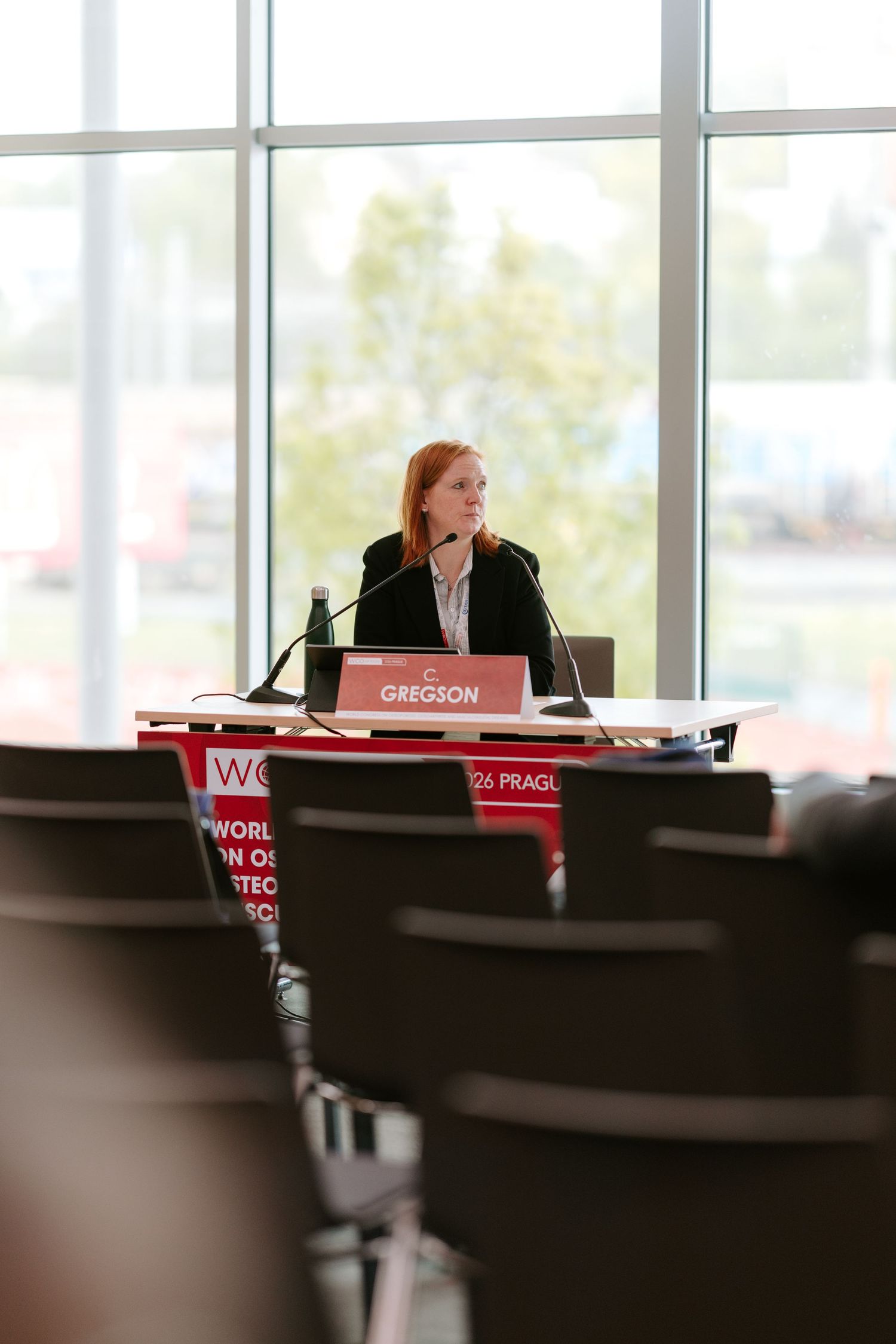 Woman named Gregson speaking at podium during World Osteoporosis Congress in Prague conference room.