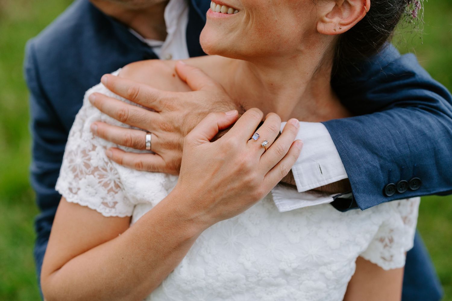 Close-up of a couple embracing on their wedding day, showing wedding rings on their hands.