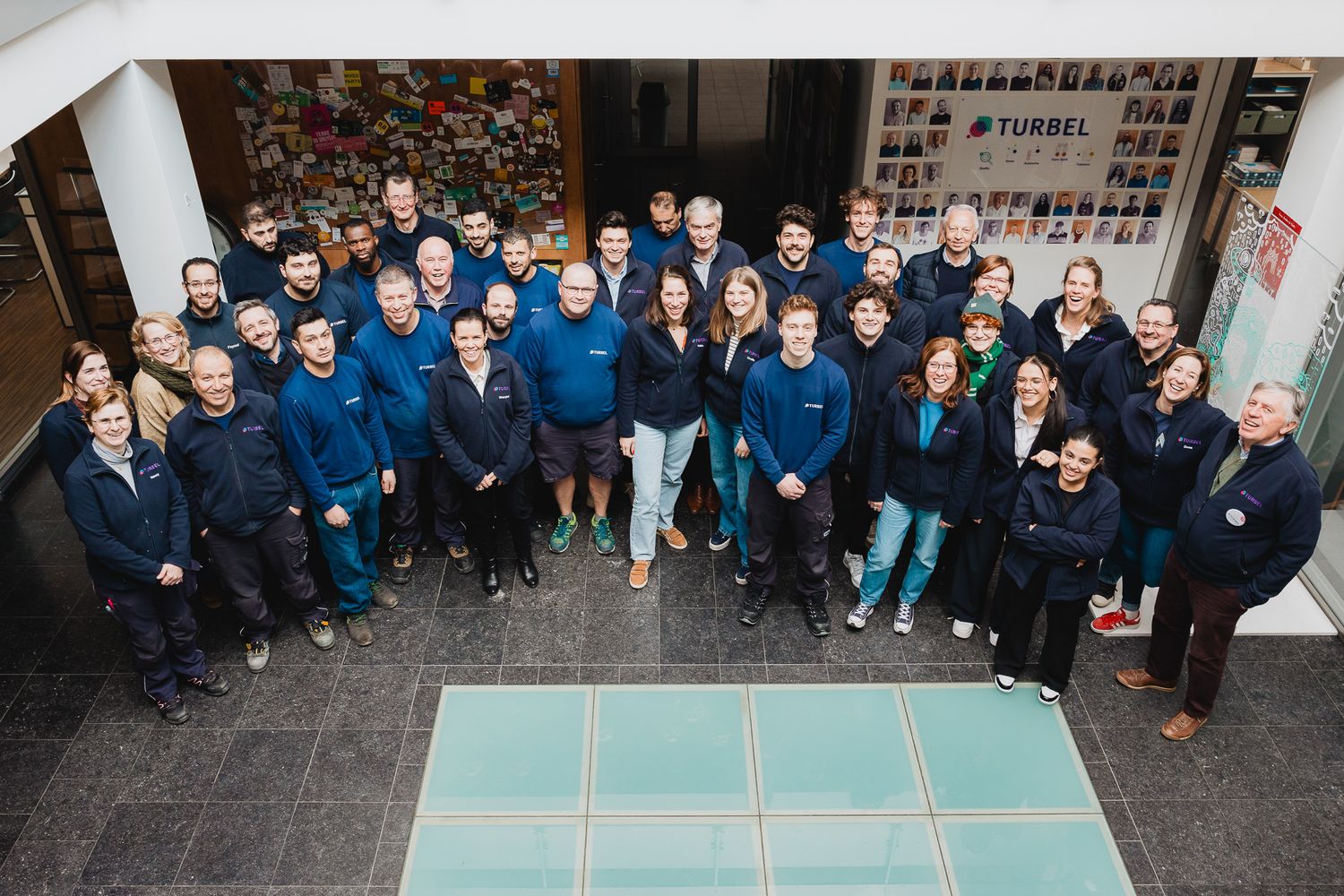 Large group of employees in blue uniforms posing for a team photo indoors.