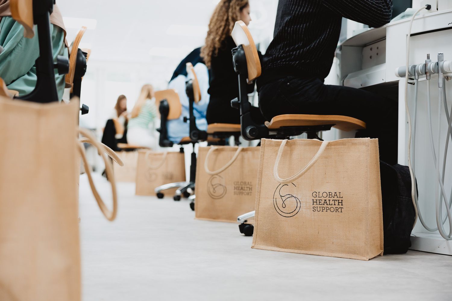 Brown paper Global Health Support branded gift bags placed on chairs at an event.