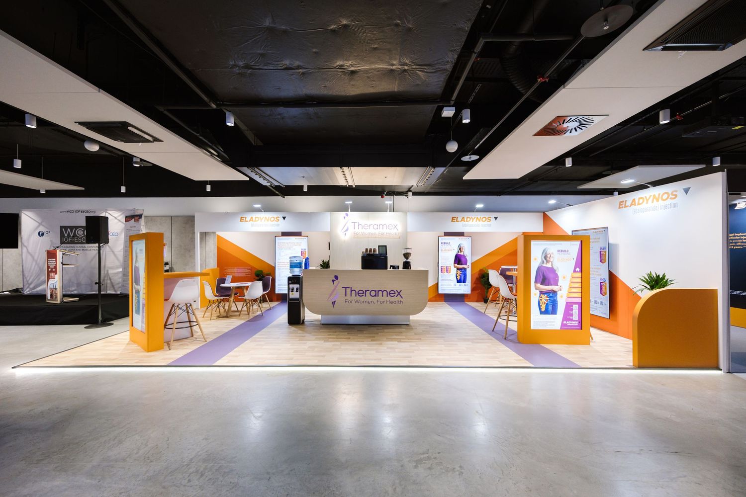 Modern exhibition booth for Theramex featuring orange and white geometric displays in a spacious hall.