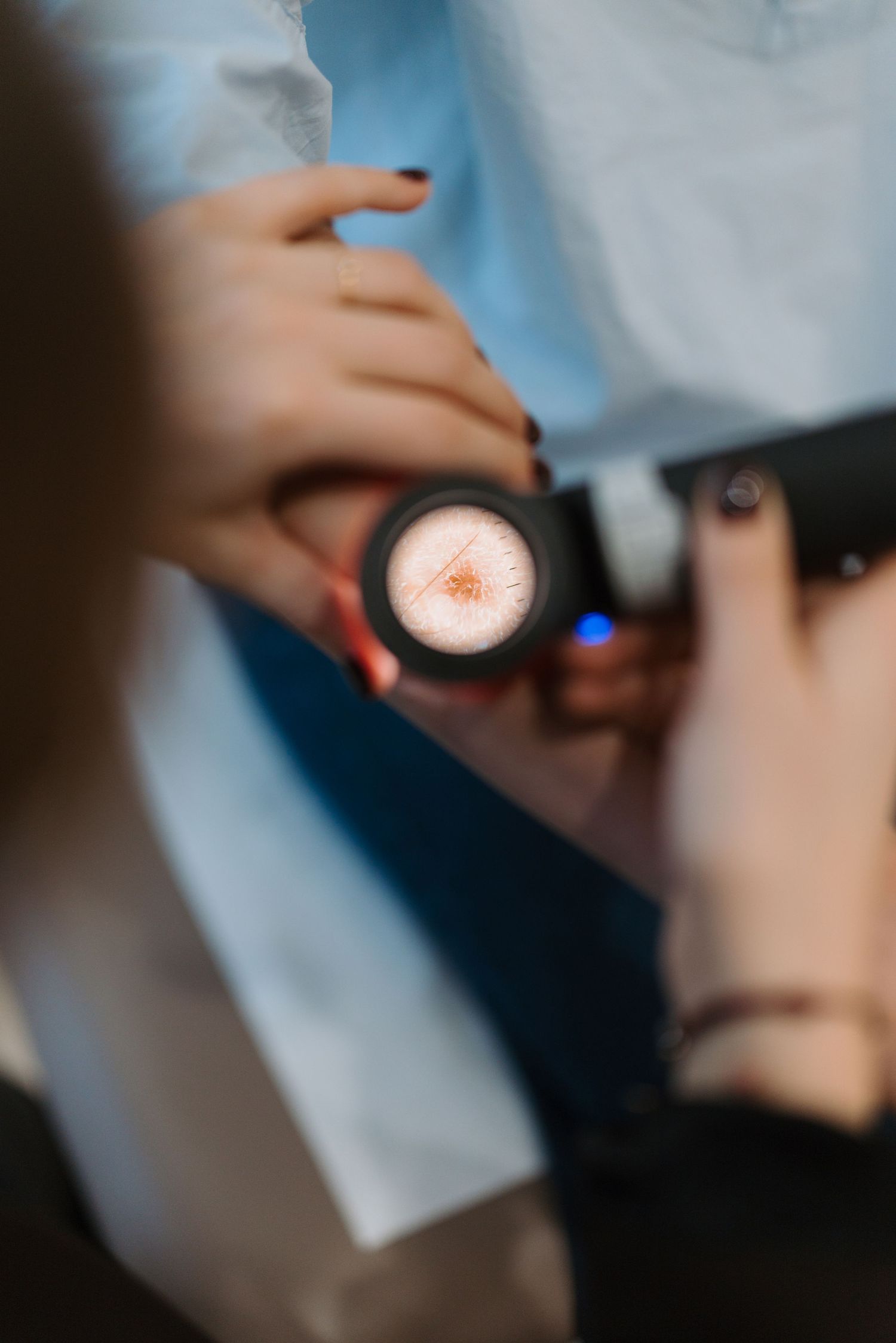 Close-up of hands holding a illuminated camera lens showing a glowing circular element during a photography session.