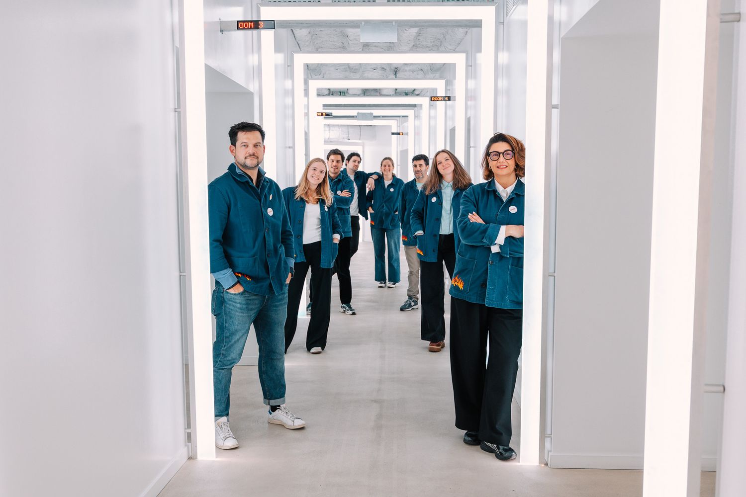 Group of professionals in teal uniforms standing confidently in a bright modern corridor.