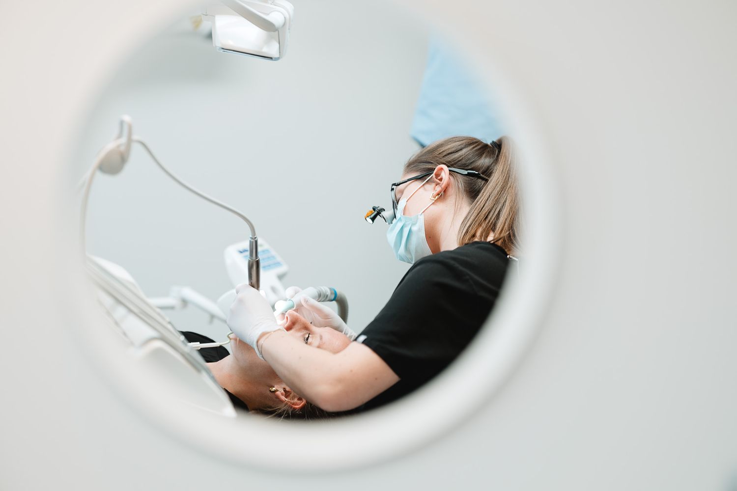 Female dentist performing dental procedure on patient in modern clinic.