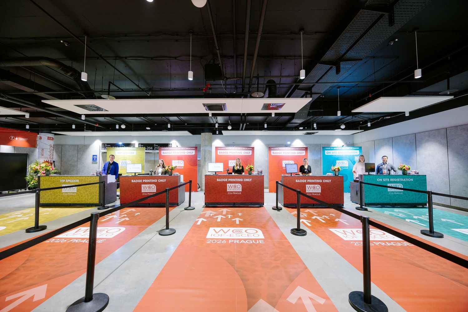 Colorful registration desks with orange, yellow, and teal counters in a modern event venue.