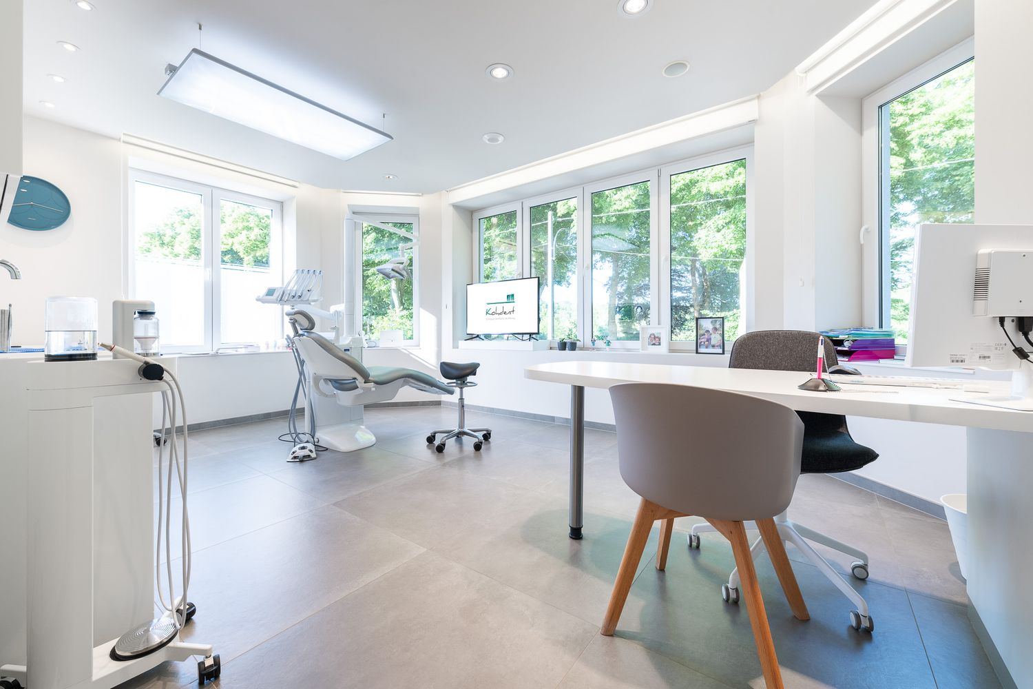 Bright modern dental office with examination chair, large windows, and clean white decor.