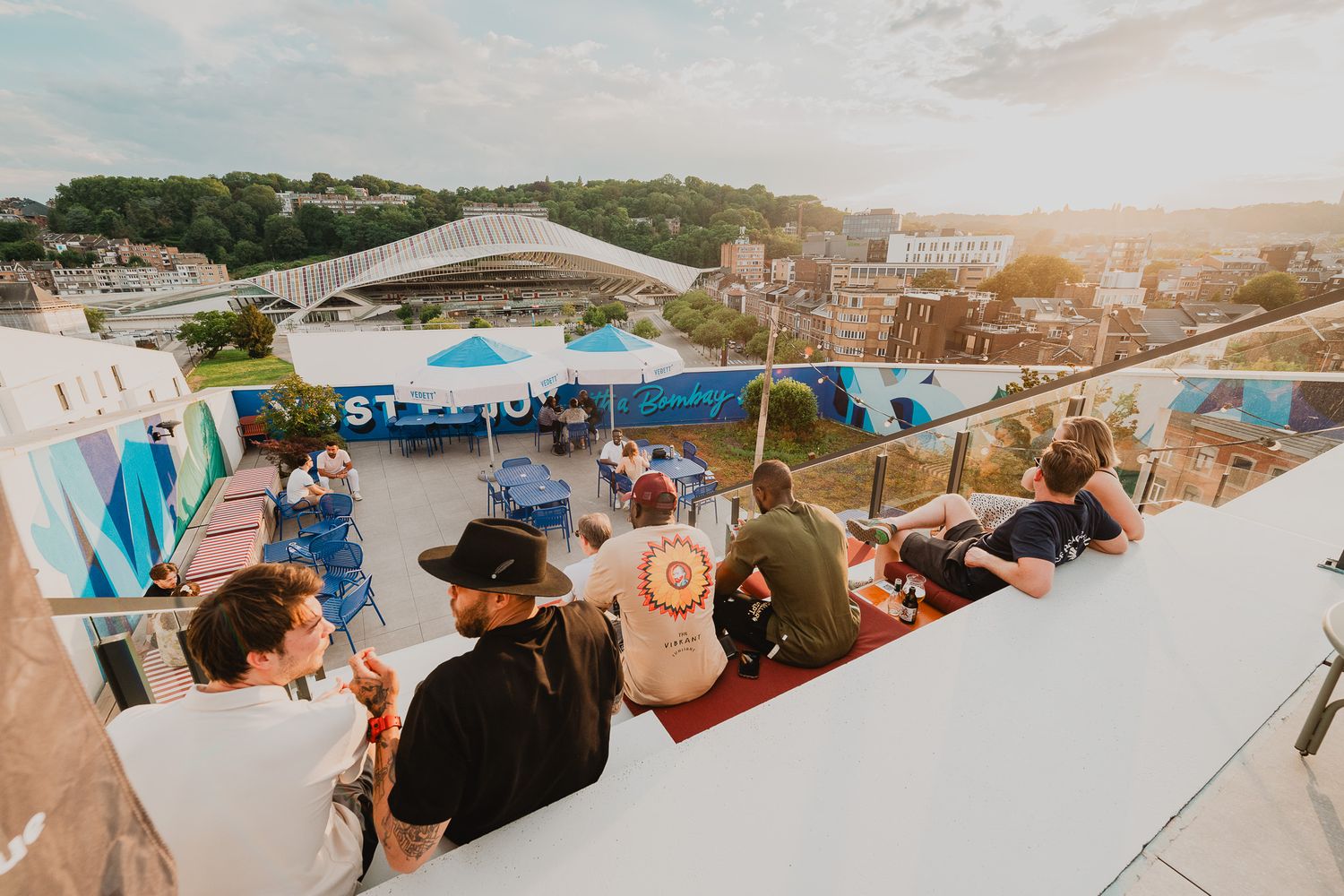 People enjoying rooftop bar event at sunset with city skyline views.