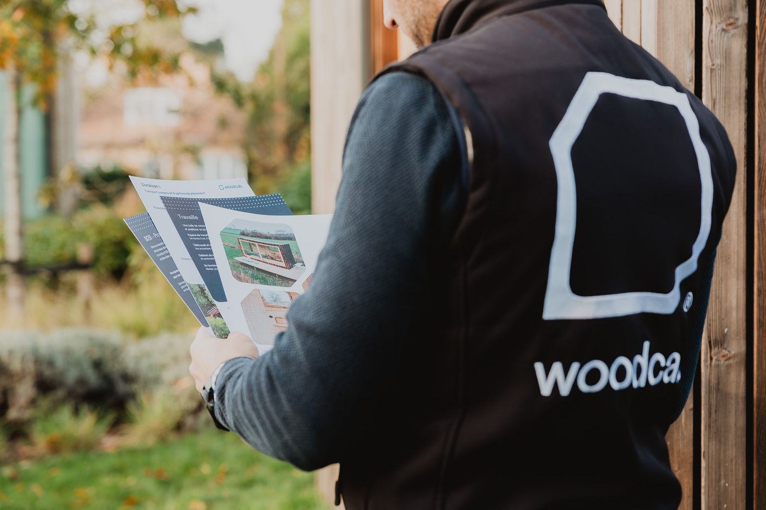 Person wearing a Woodca branded black vest while reviewing documents outdoors.
