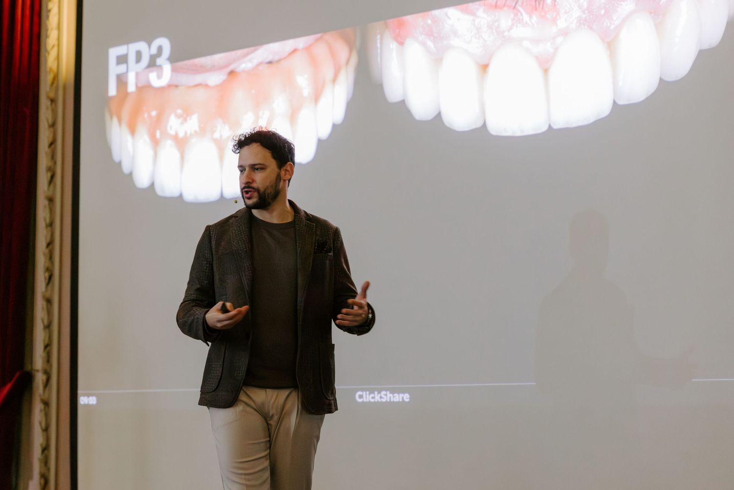 Dental professional presenting FP3 dental prosthetics on a large projection screen during a conference.