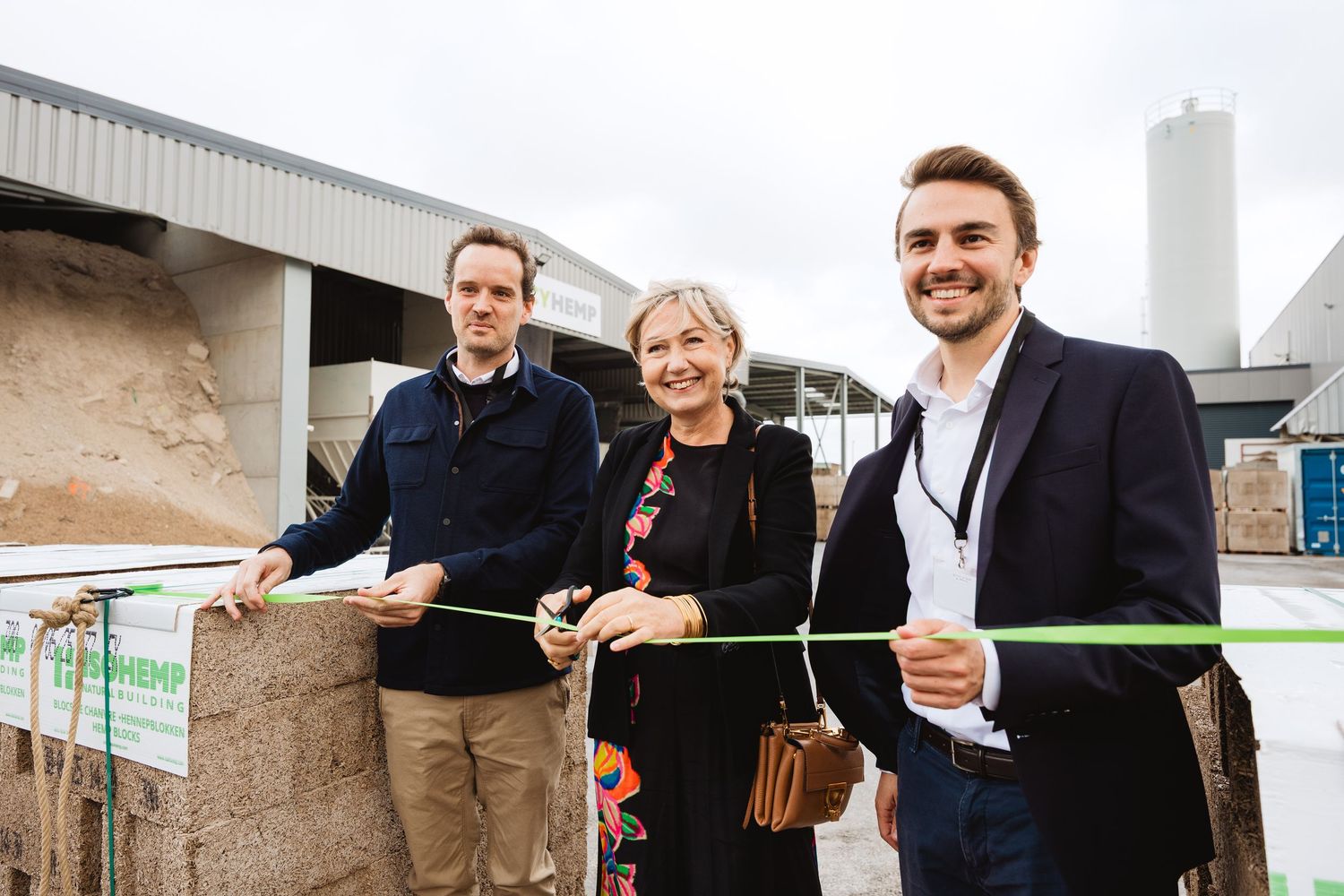 Three people cutting green ribbon at BioHemp facility grand opening ceremony.