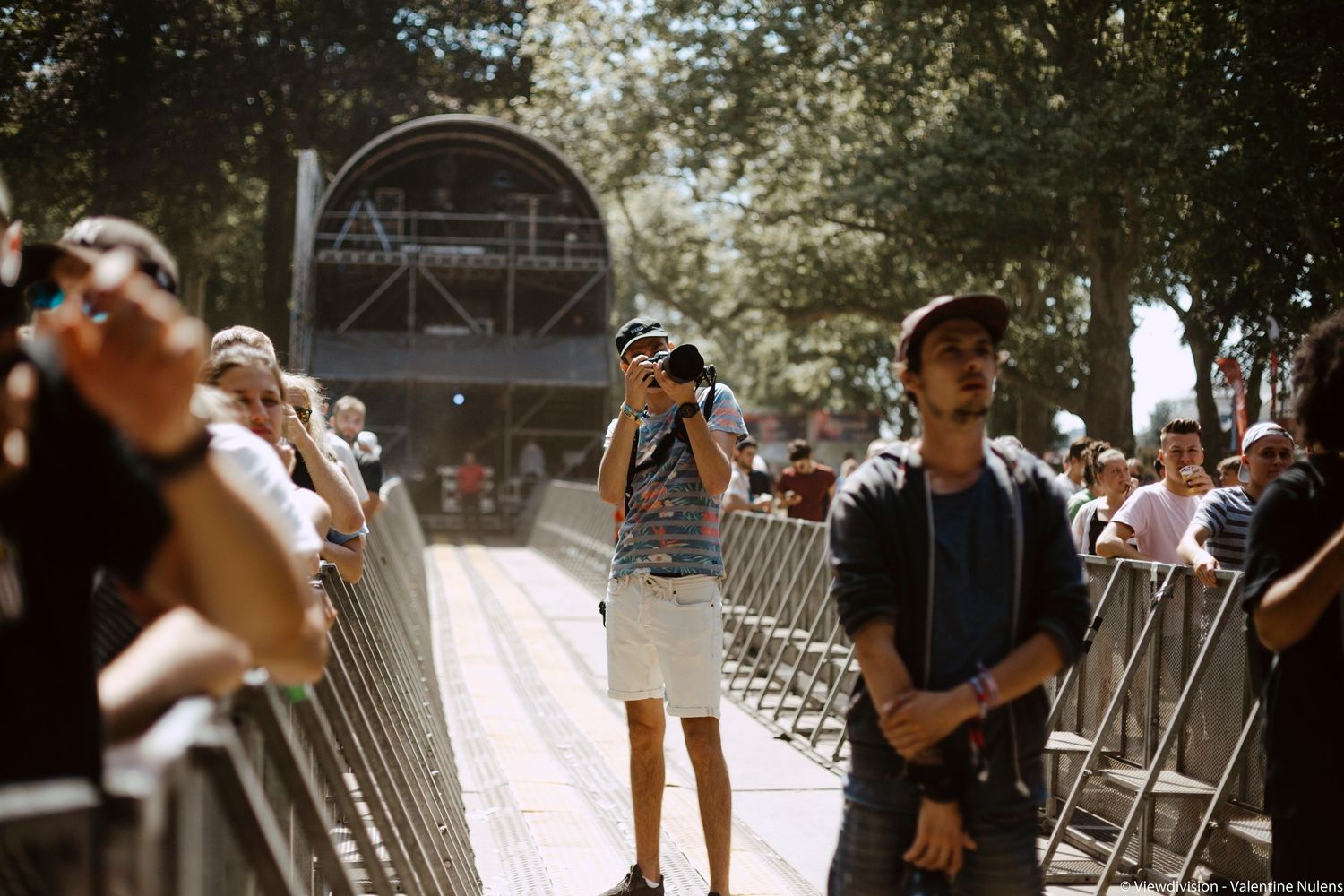 Photographer capturing moments at a crowded outdoor festival event on a sunny summer day.