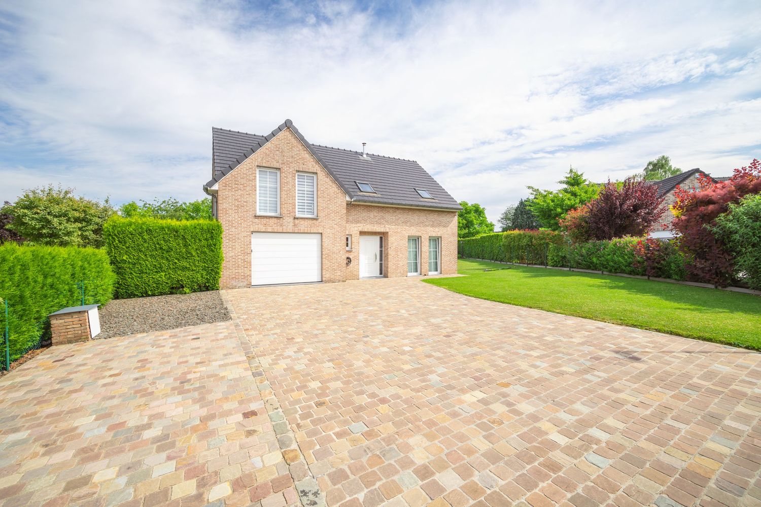 Elegant brick detached house with a spacious paved driveway and well-maintained garden.