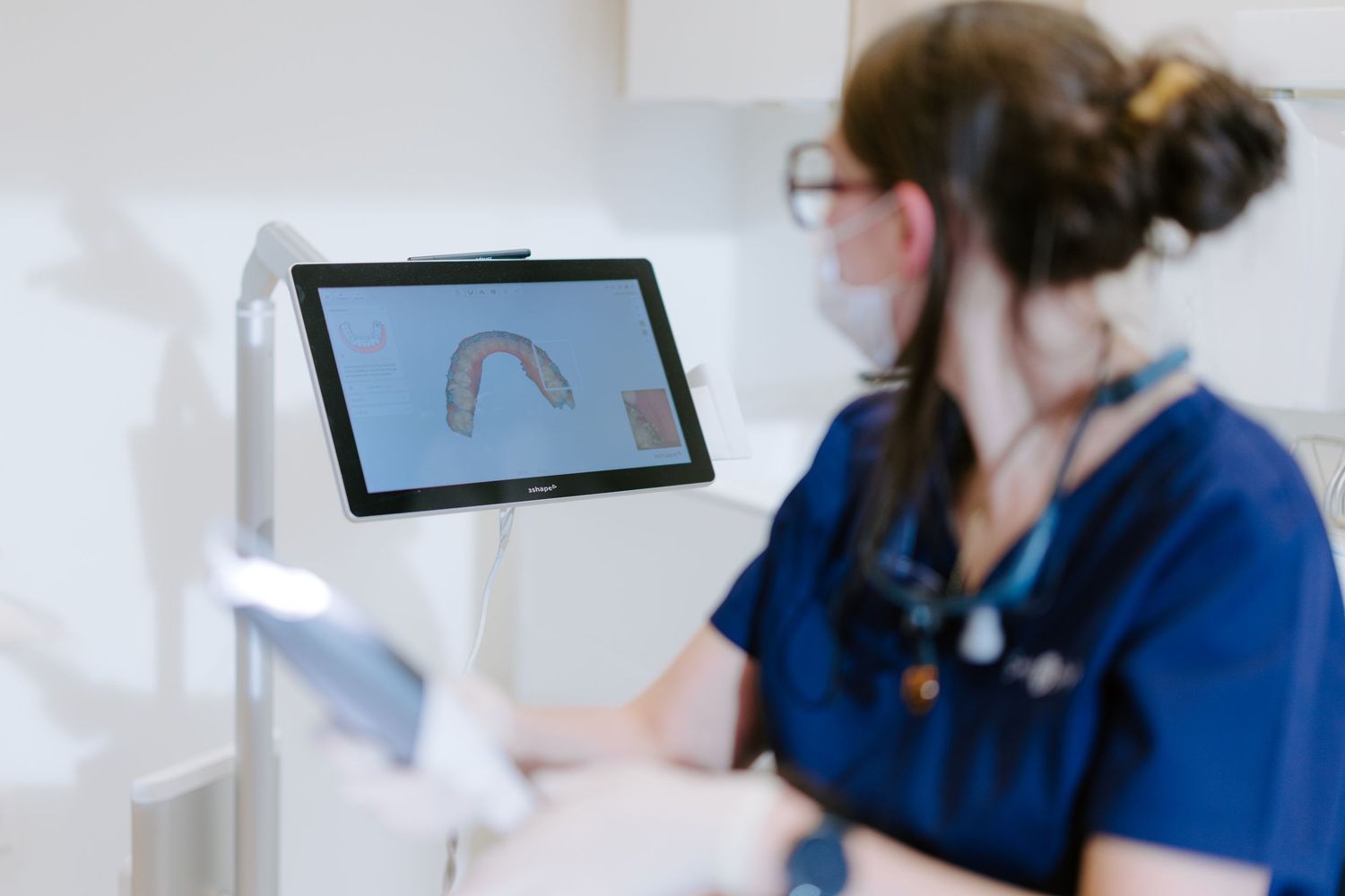 Dental technician reviews a 3D tooth scan on a monitor during a modern digital dentistry consultation.