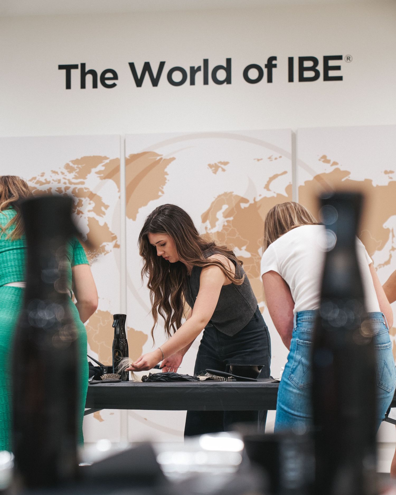 Candid view of an education workshop with a stylist working at a table and tools in the foreground inside an open studio
