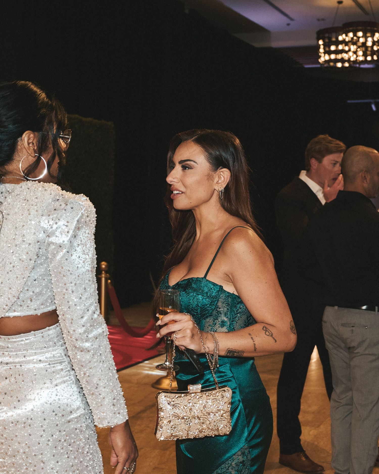 Guest dressed up at a gala style event, talking with others during cocktail hour.