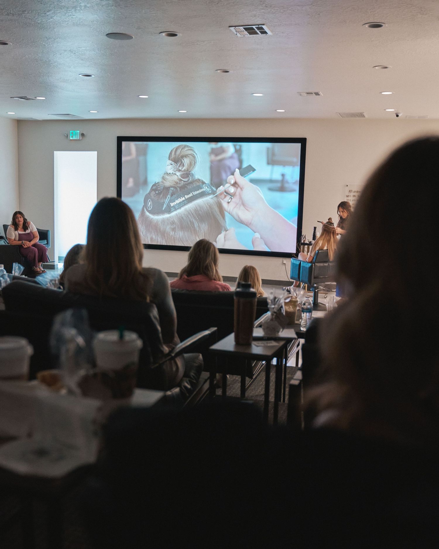 Audience seated in a studio classroom watching a live education demonstration on a projector screen