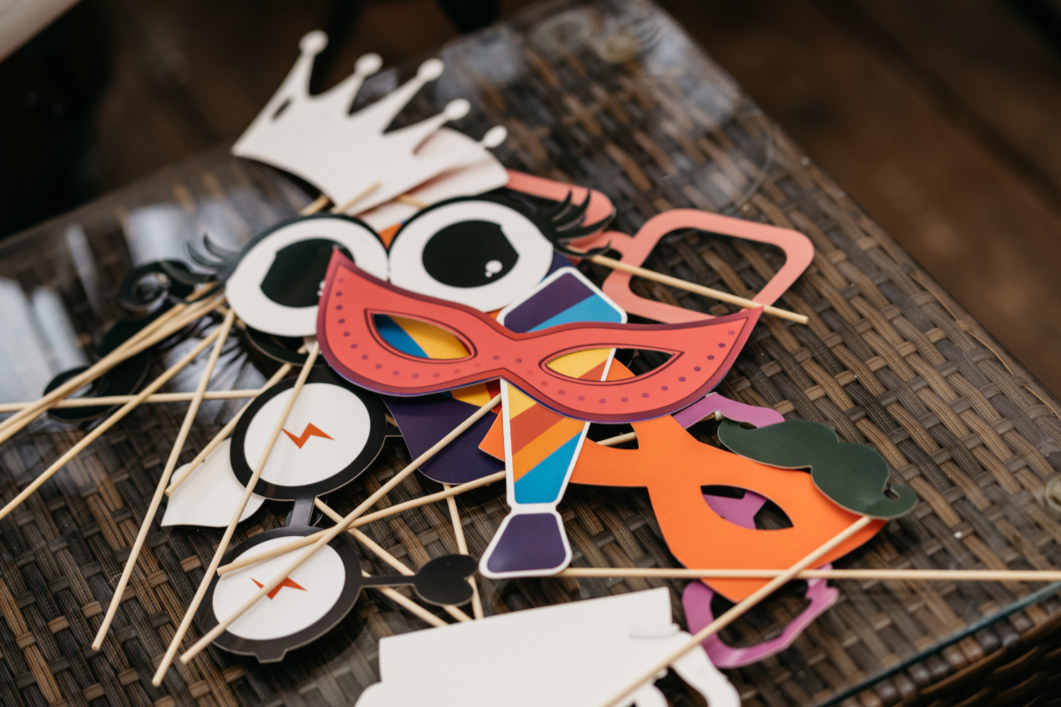 Photo Booth rental in O'Fallon Missouri showing Collection of colorful paper photo booth props including masks & glasses on wooden surface.