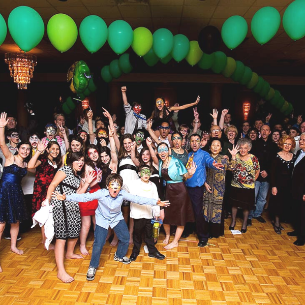 Barmiltzha Photo of crowd enjoying Photo Booth rental, Large crowd celebrating under green balloon arch on wooden dance floor. Saint Charles