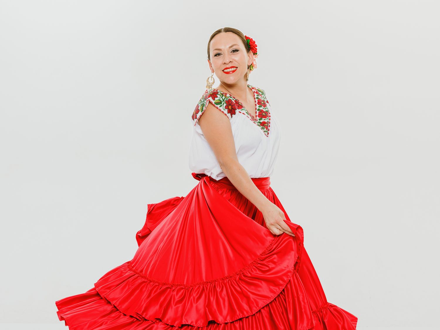 Dancer in traditional red and white folk costume twirling her full skirt.