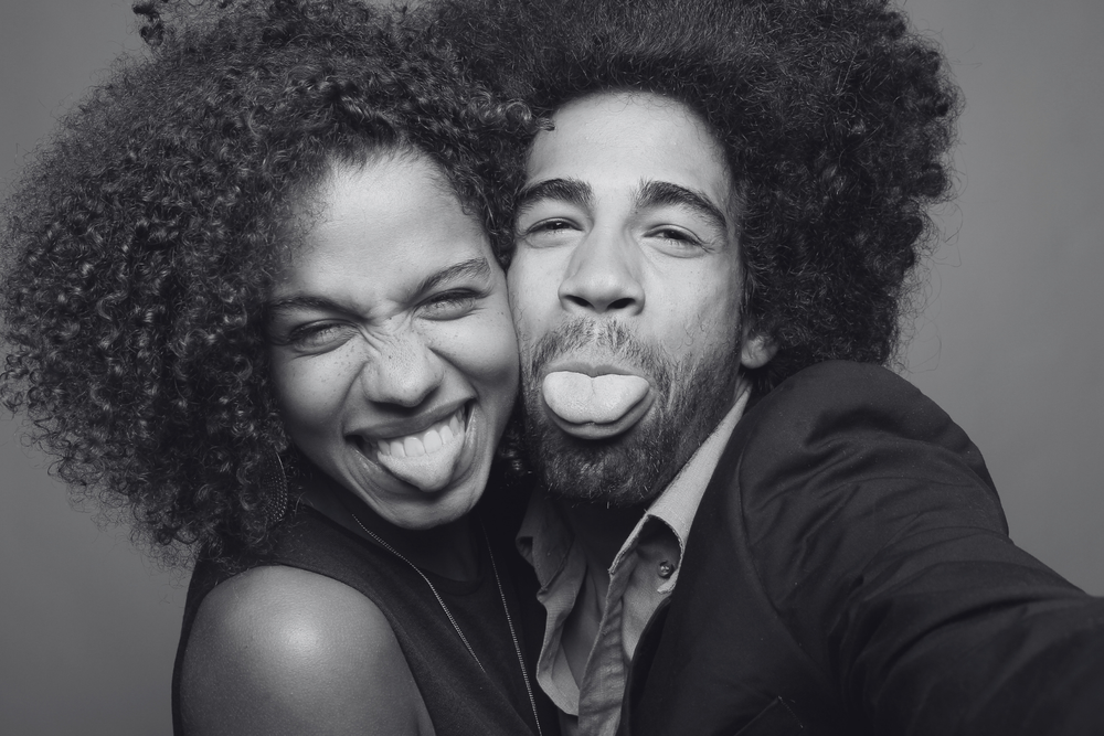 A joyful black and white portrait of a couple making silly faces and laughing together.ofallon-mo-photo-booth-wedding-reception